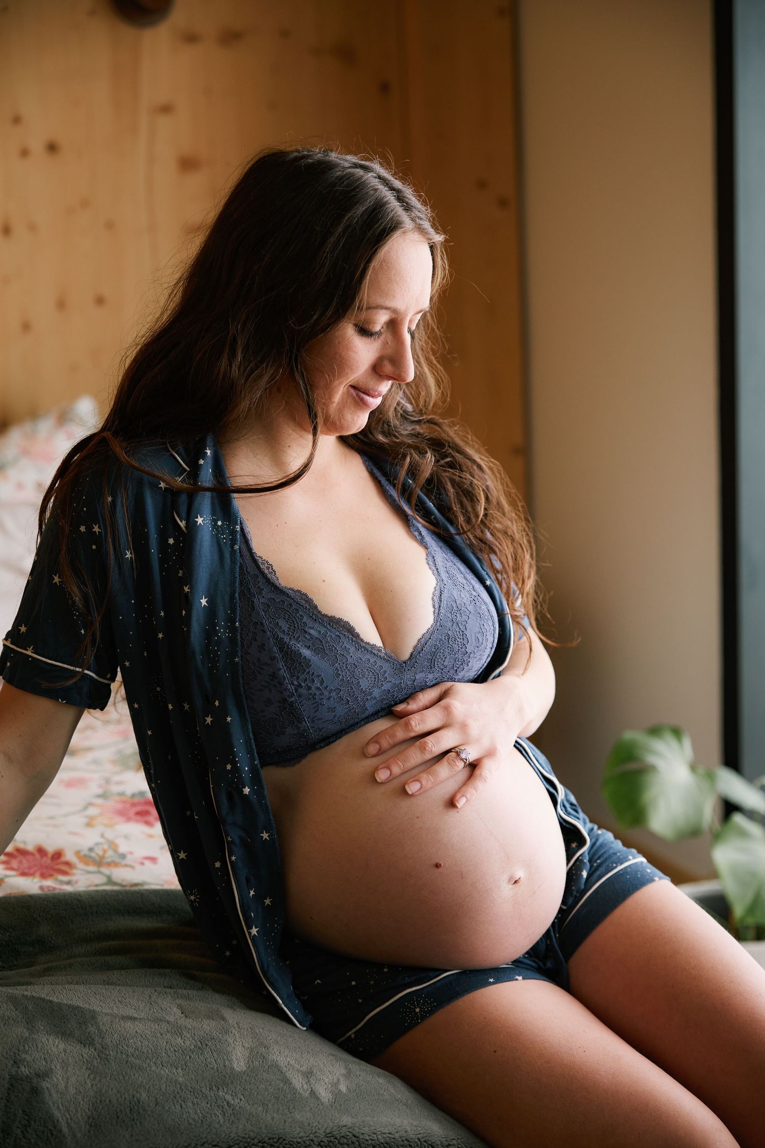 A maternity photo showing an expectant mother in lingerie by a window.