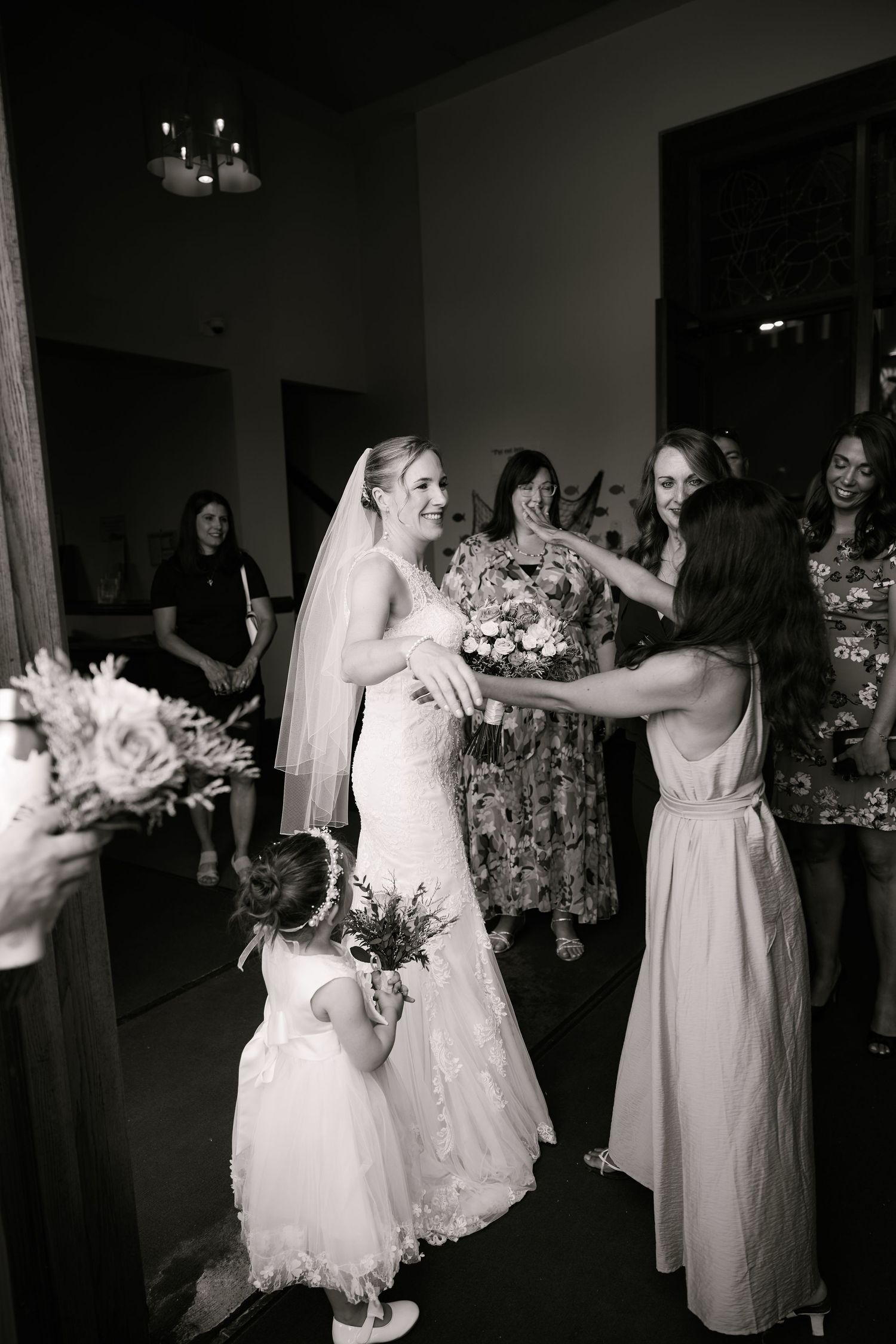 Black and white photo of bridesmaids celebrating during wedding preparations indoors.