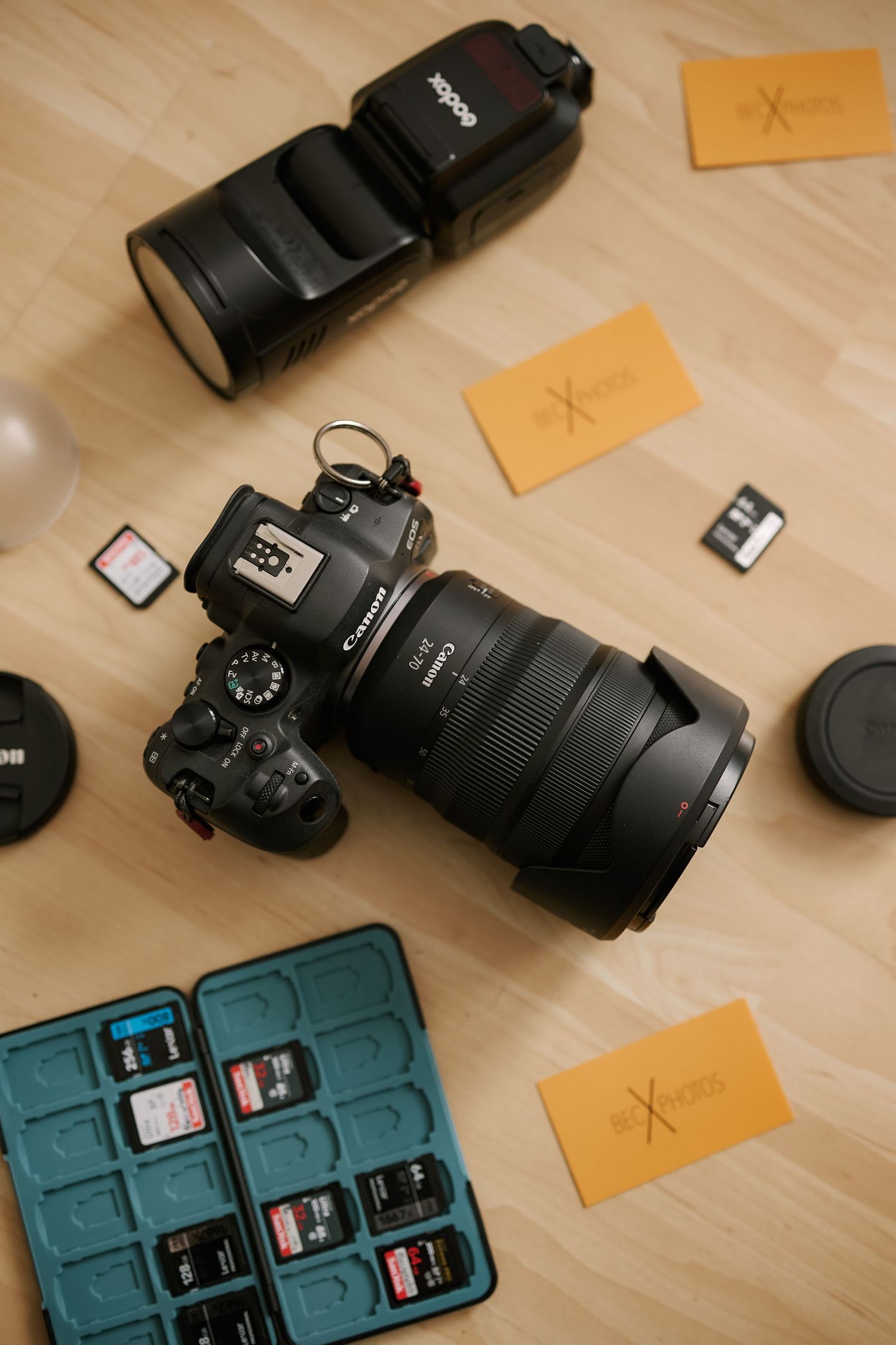 Photography equipment including lenses and memory cards displayed on wooden surface.