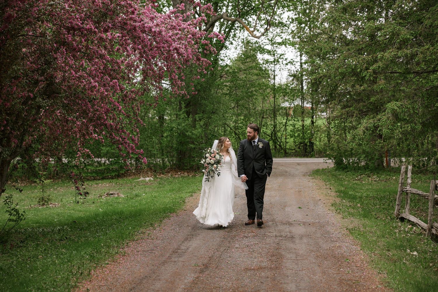 Couple walking down a tree-lined path with spring blossoms in bloom.