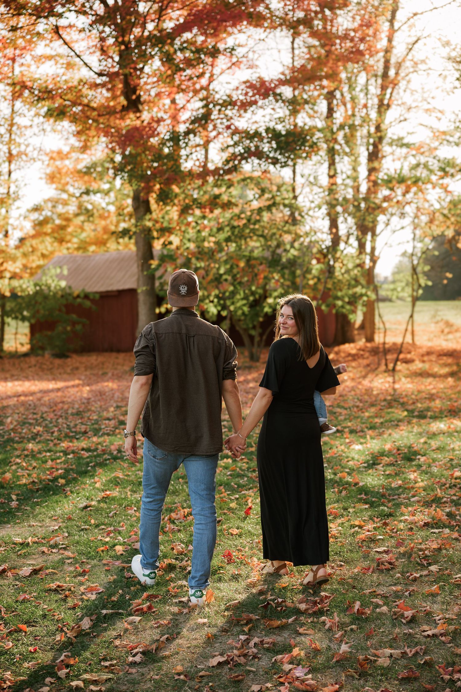 Couple walking through autumn forest with fallen leaves and rustic scenery.