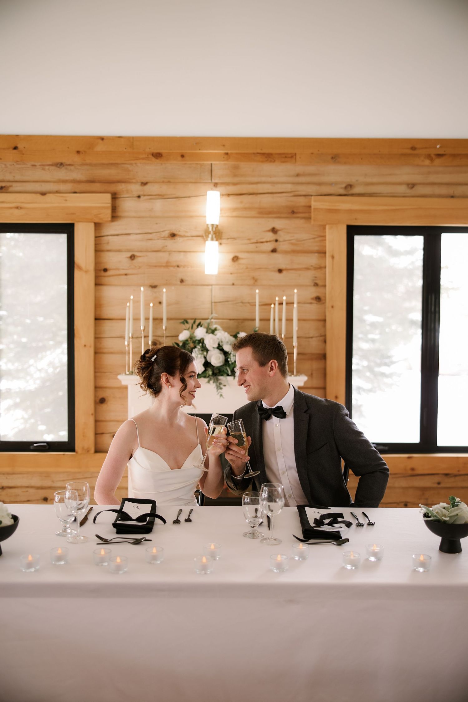 Intimate wedding reception moment at a rustic wooden head table with candlelight.