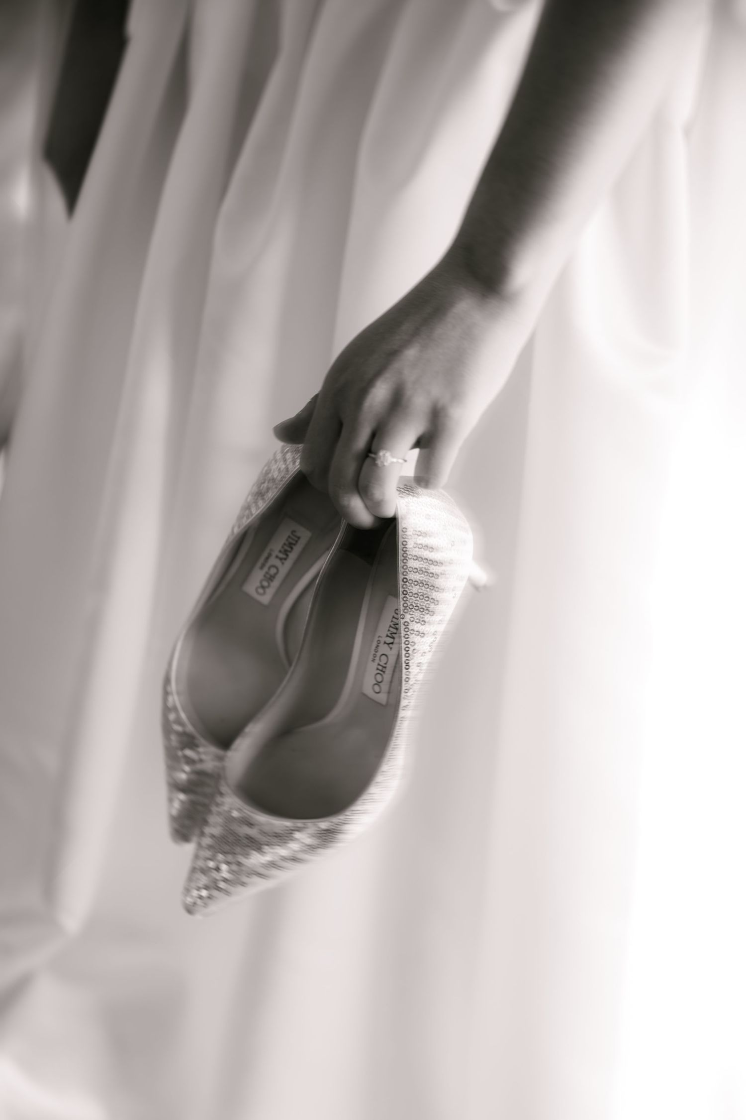 Artistic detail shot of bridal shoes against flowing white wedding dress fabric.