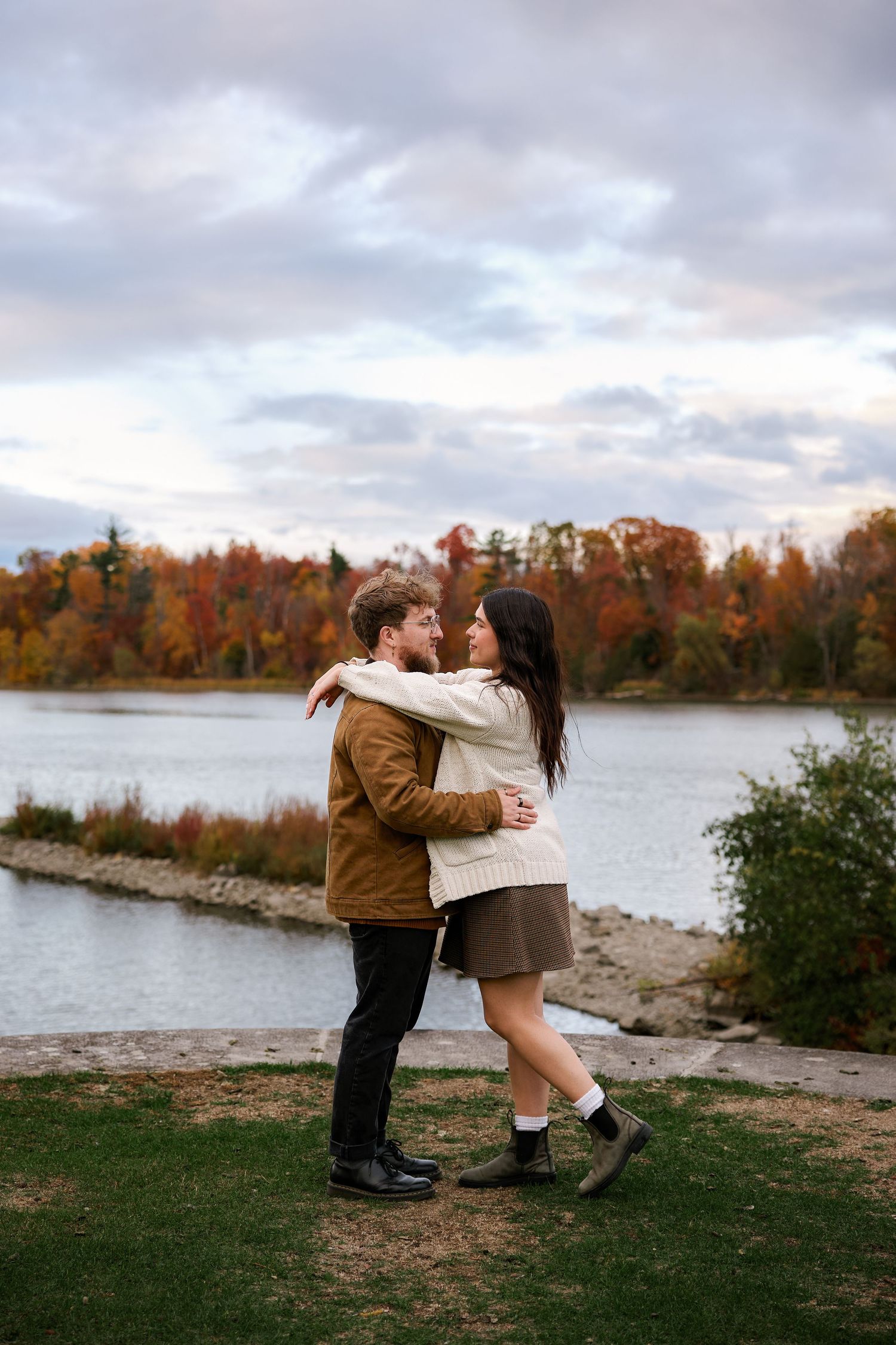 Couple plays and dances together near an autumn lake at sunset.