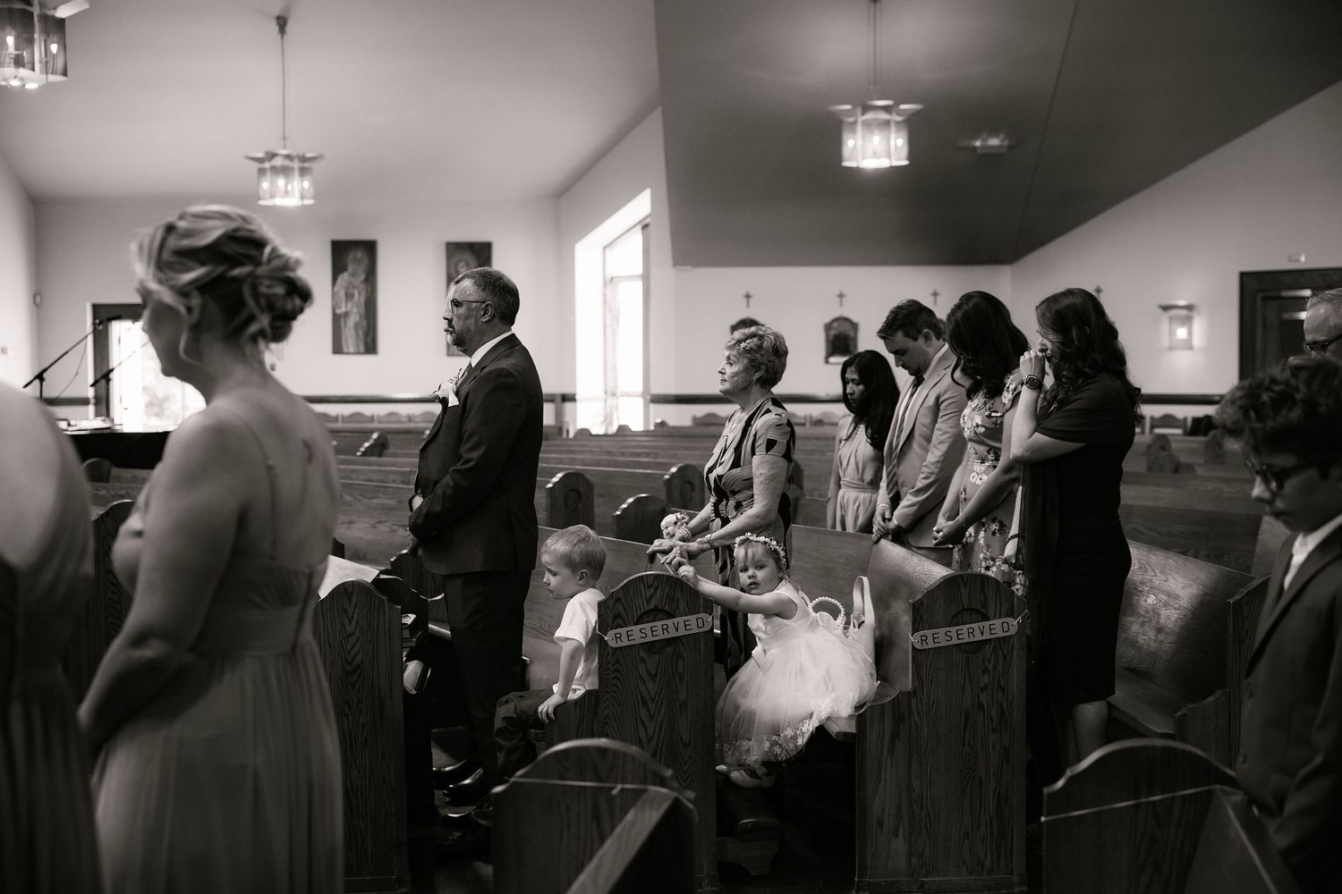Black and white photo of a church ceremony with attendees gathered in wooden pews.