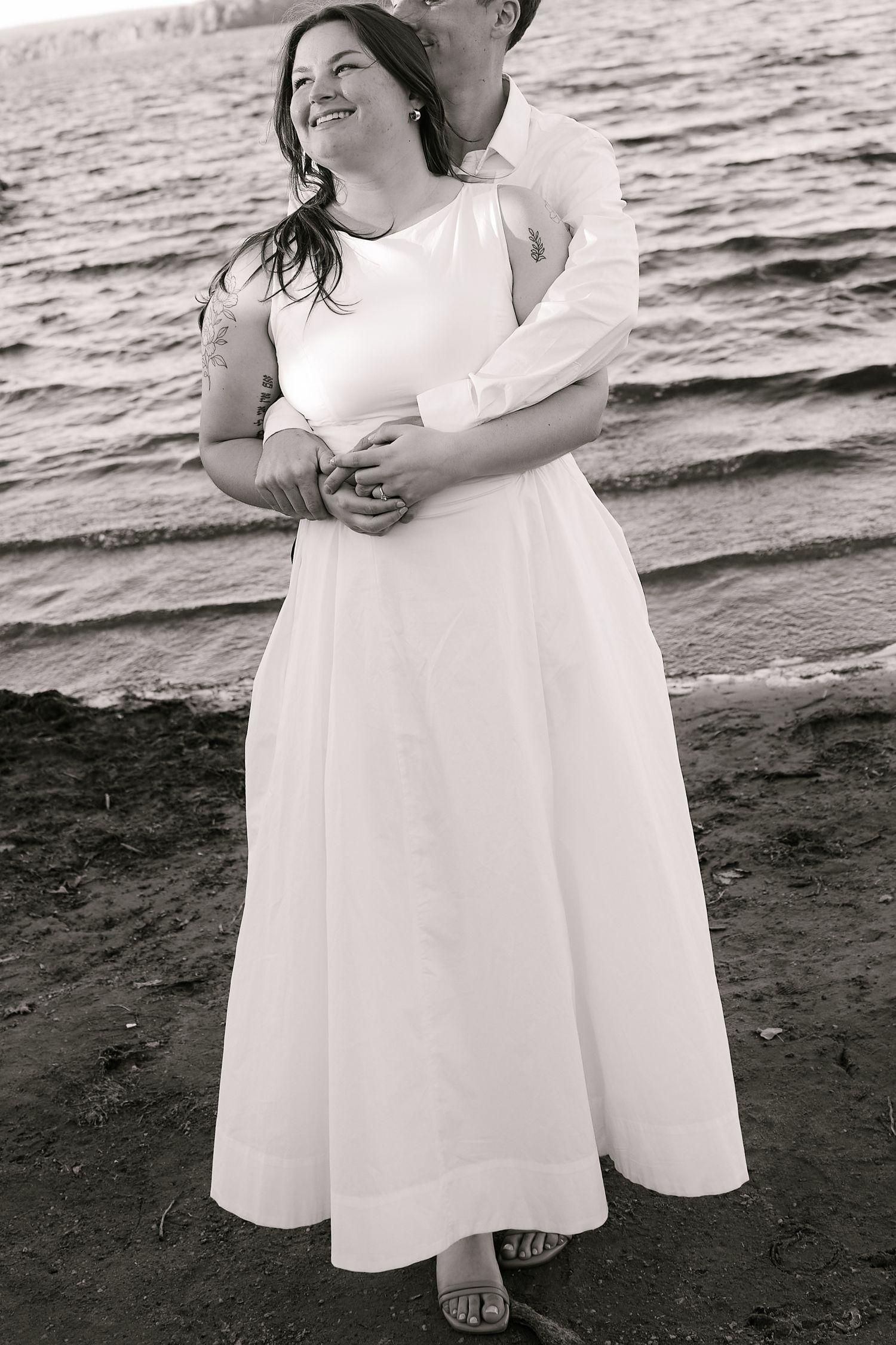 Black and white beach portraits showing tender moments between a couple in white attire.