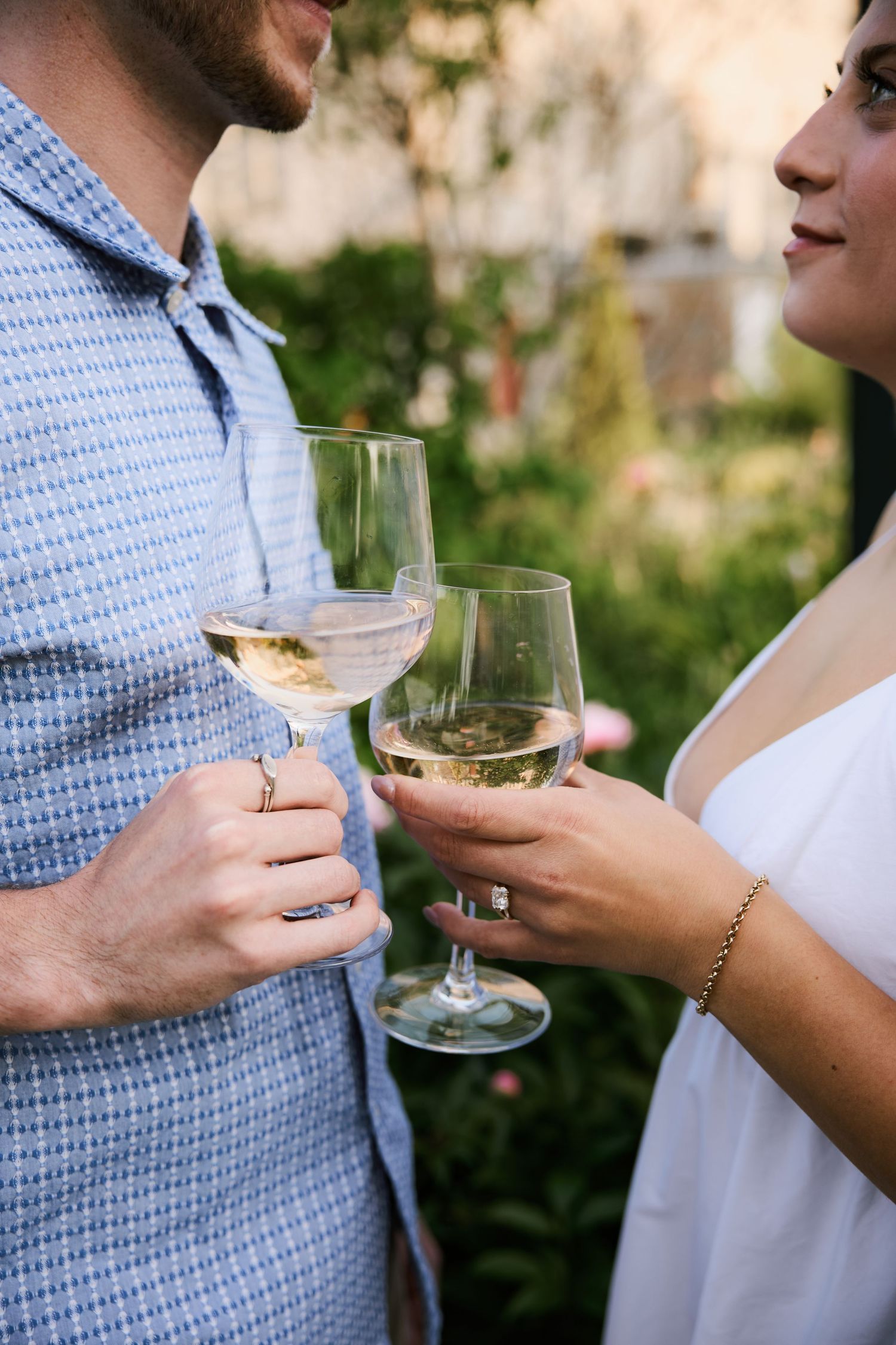 Two people hold wine glasses while having an intimate conversation outdoors.