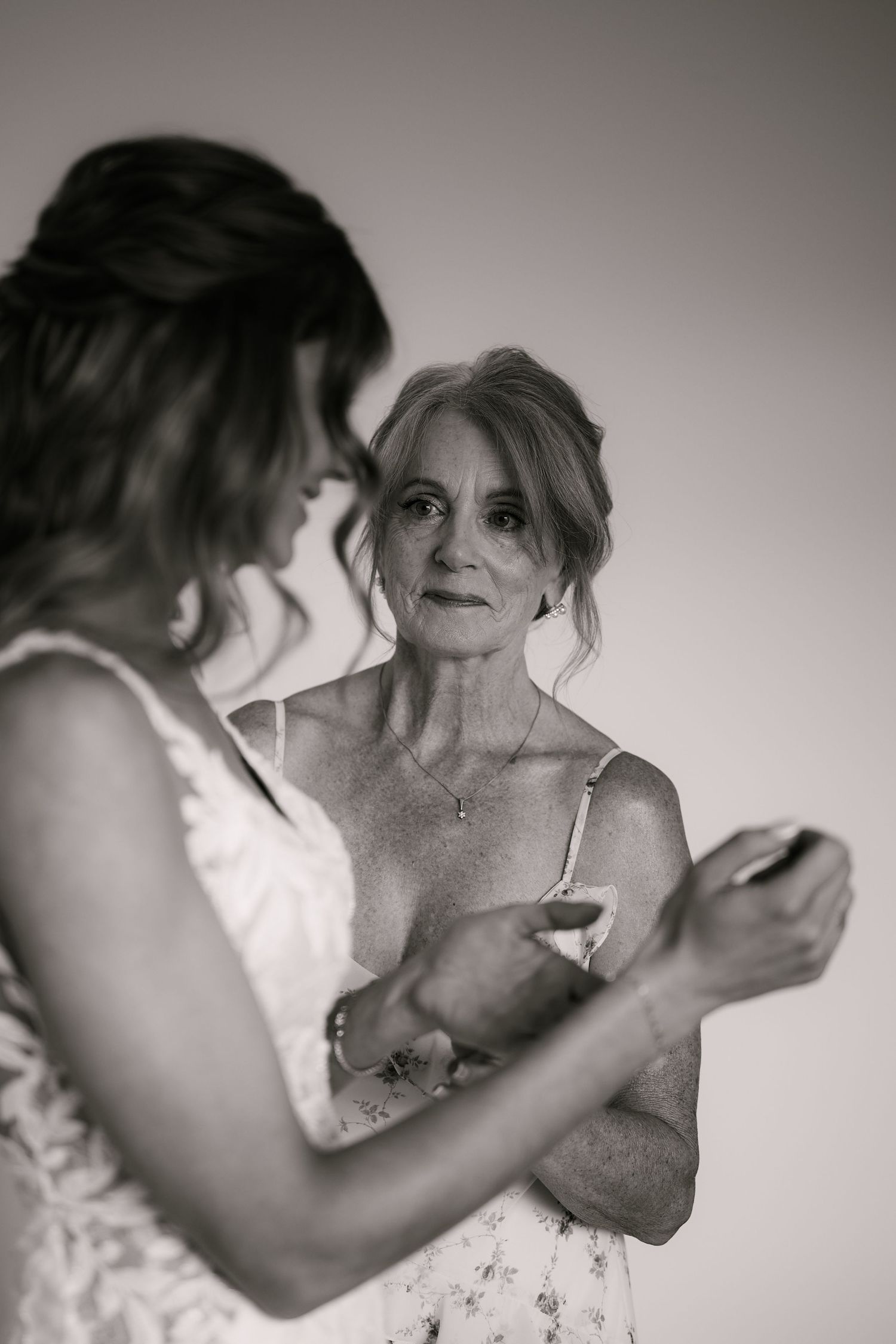 Black and white photo of a bride and older woman sharing a tender moment while getting ready for a wedding.