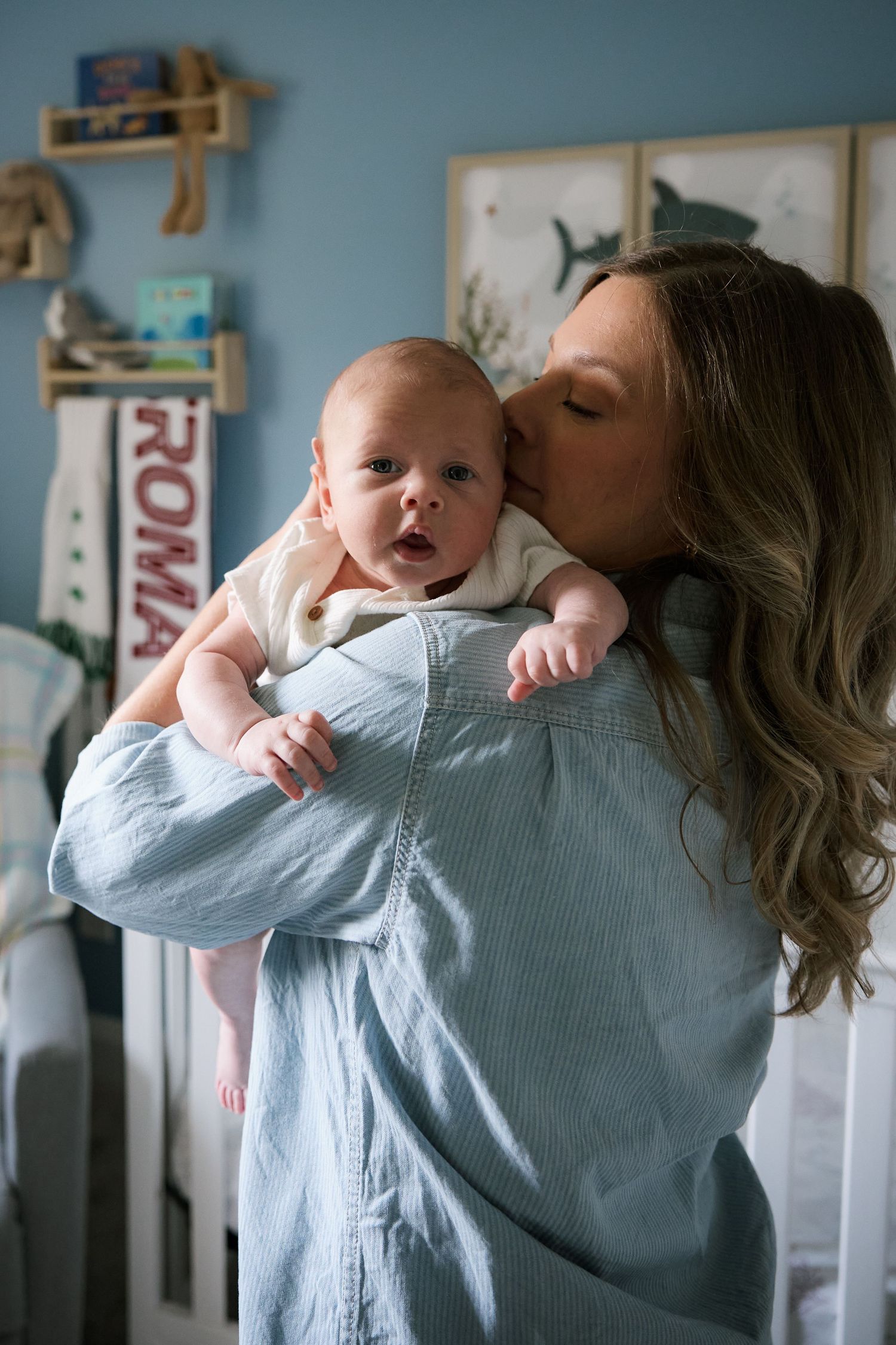 Tender moment in a blue nursery room with baby and caregiver.