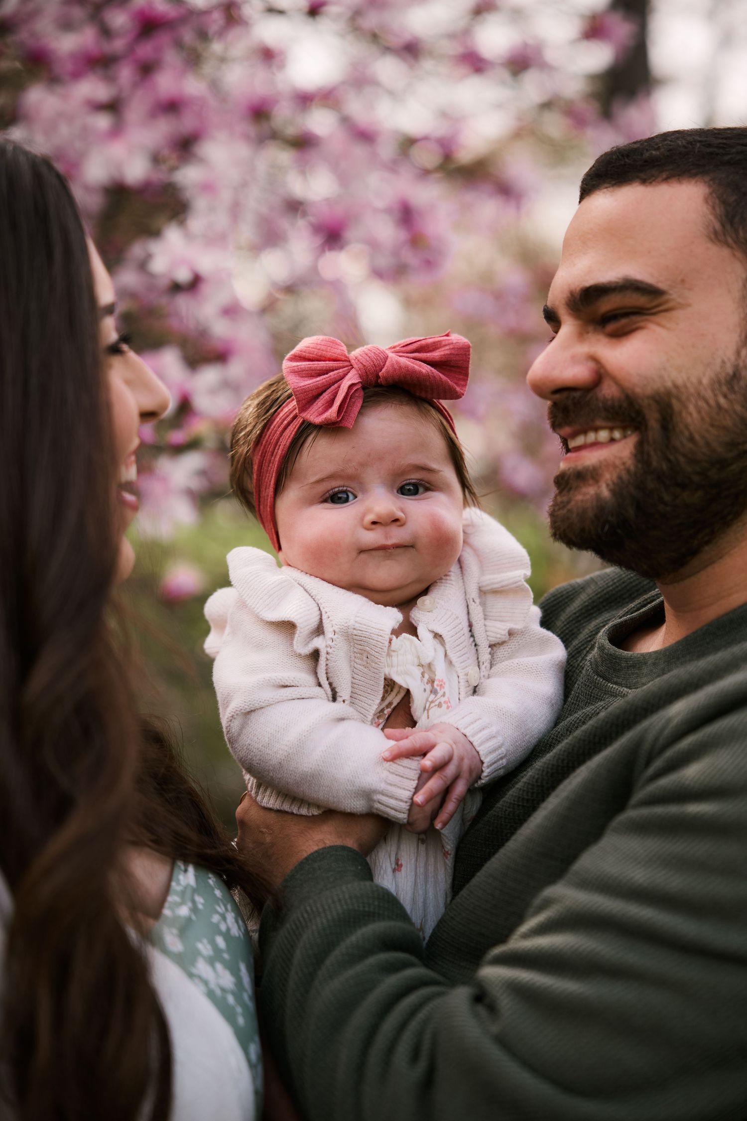 A family shares a joyful moment together under pink flowering magnolia trees.