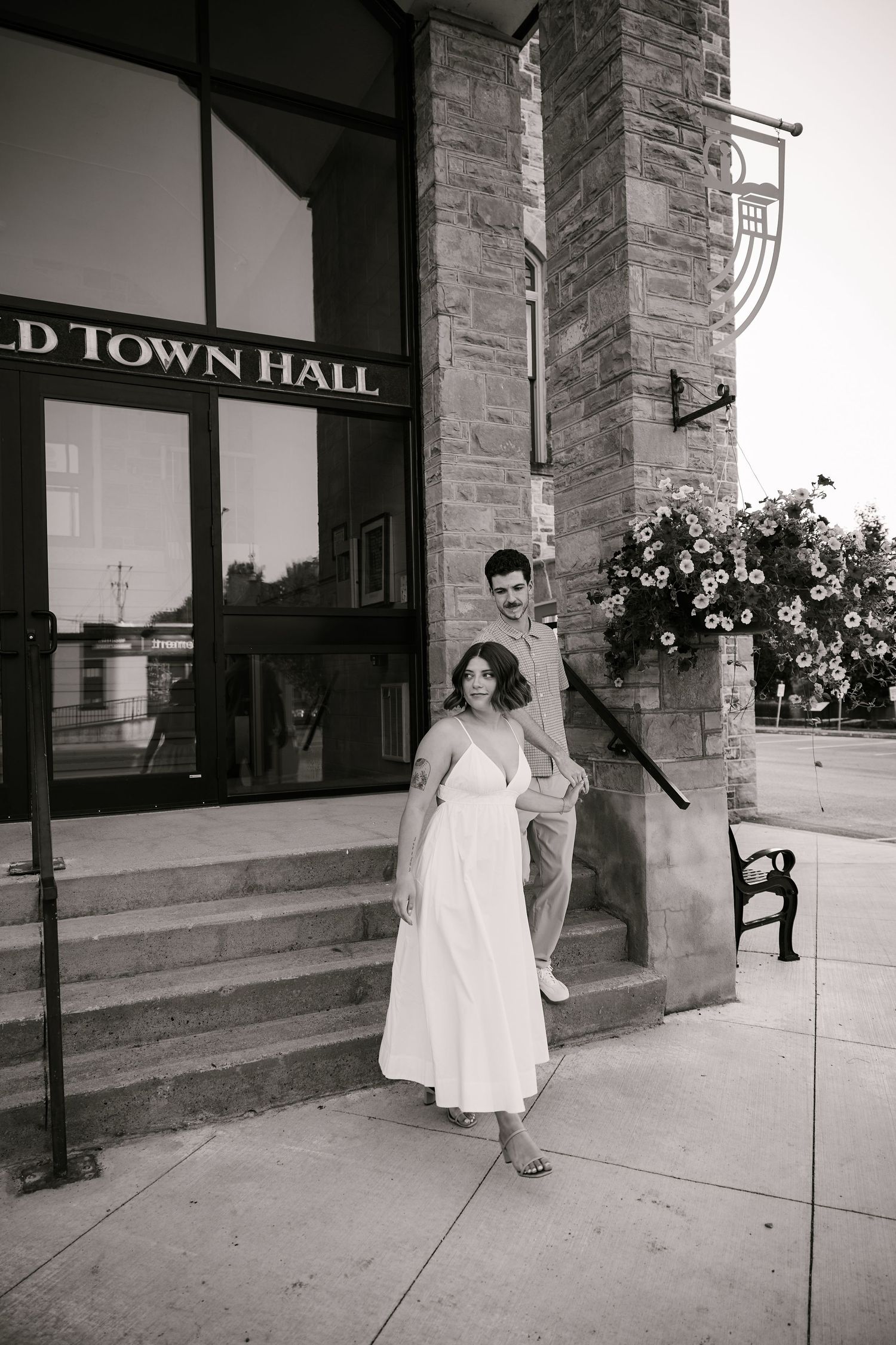 A vintage-style photo of a couple posing outside an old town hall building.