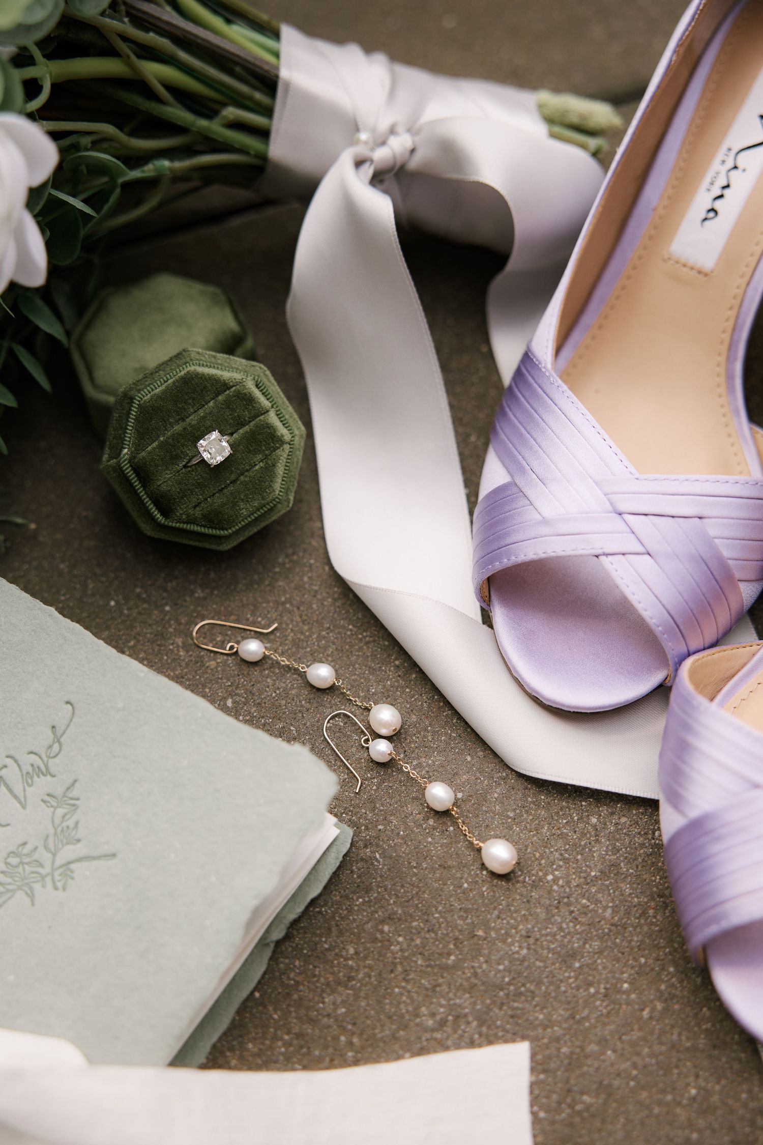 Wedding accessories including lilac shoes, pearl earrings, and velvet ring box.