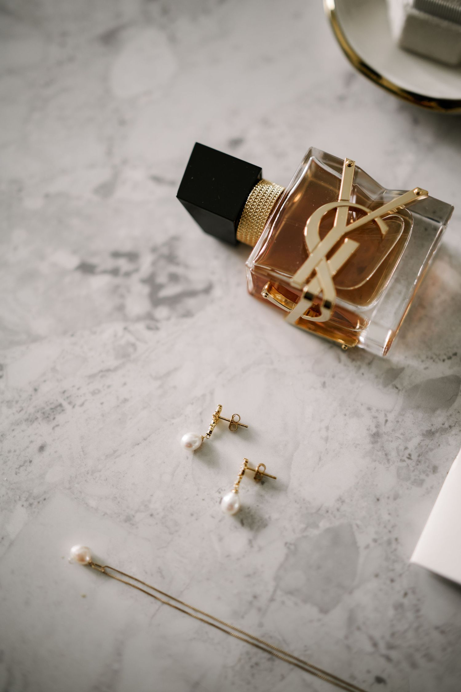Gold designer belt buckle and accessories displayed on marble surface.