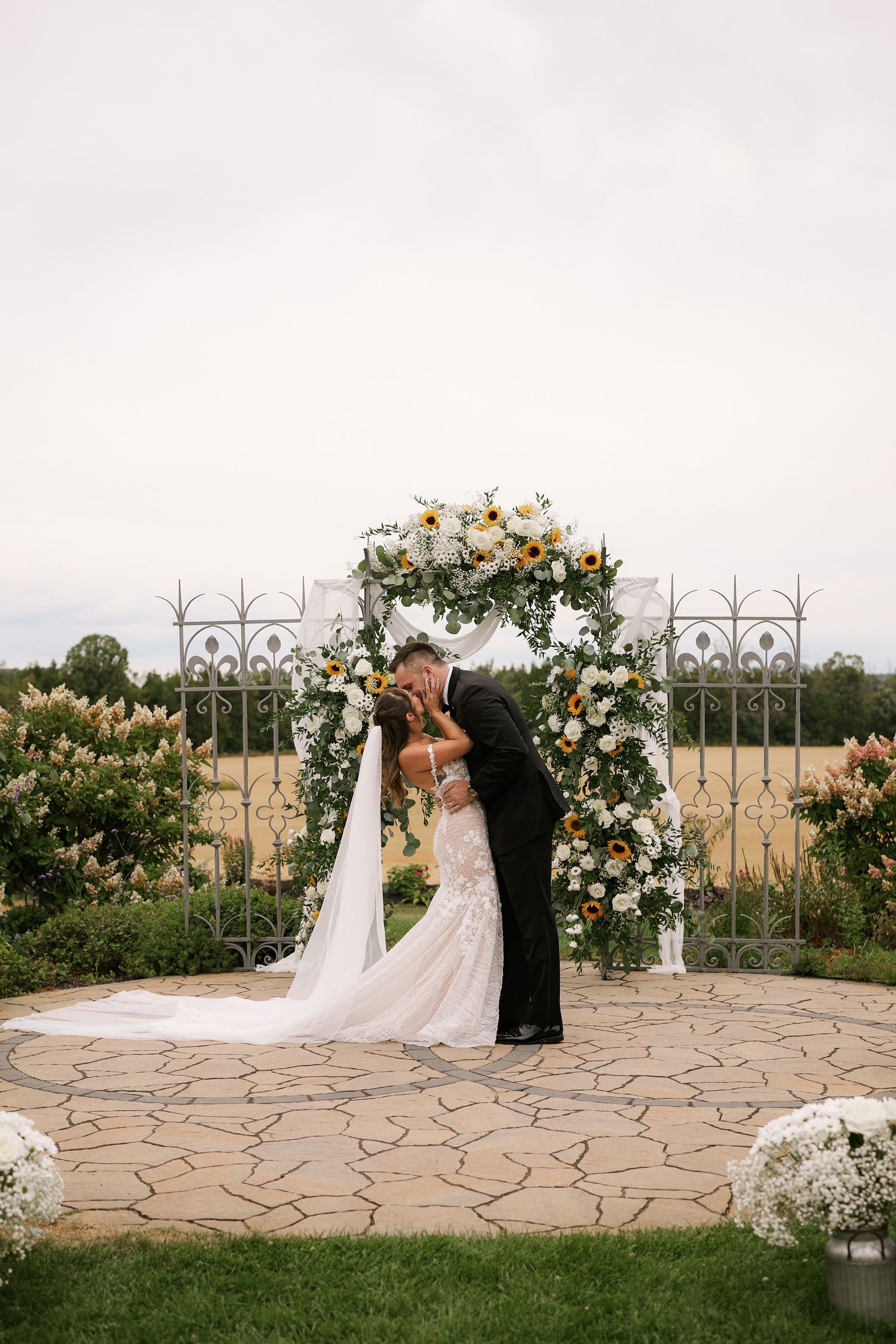 Wedding ceremony setup with floral arch and stone patio overlooking scenic countryside views.