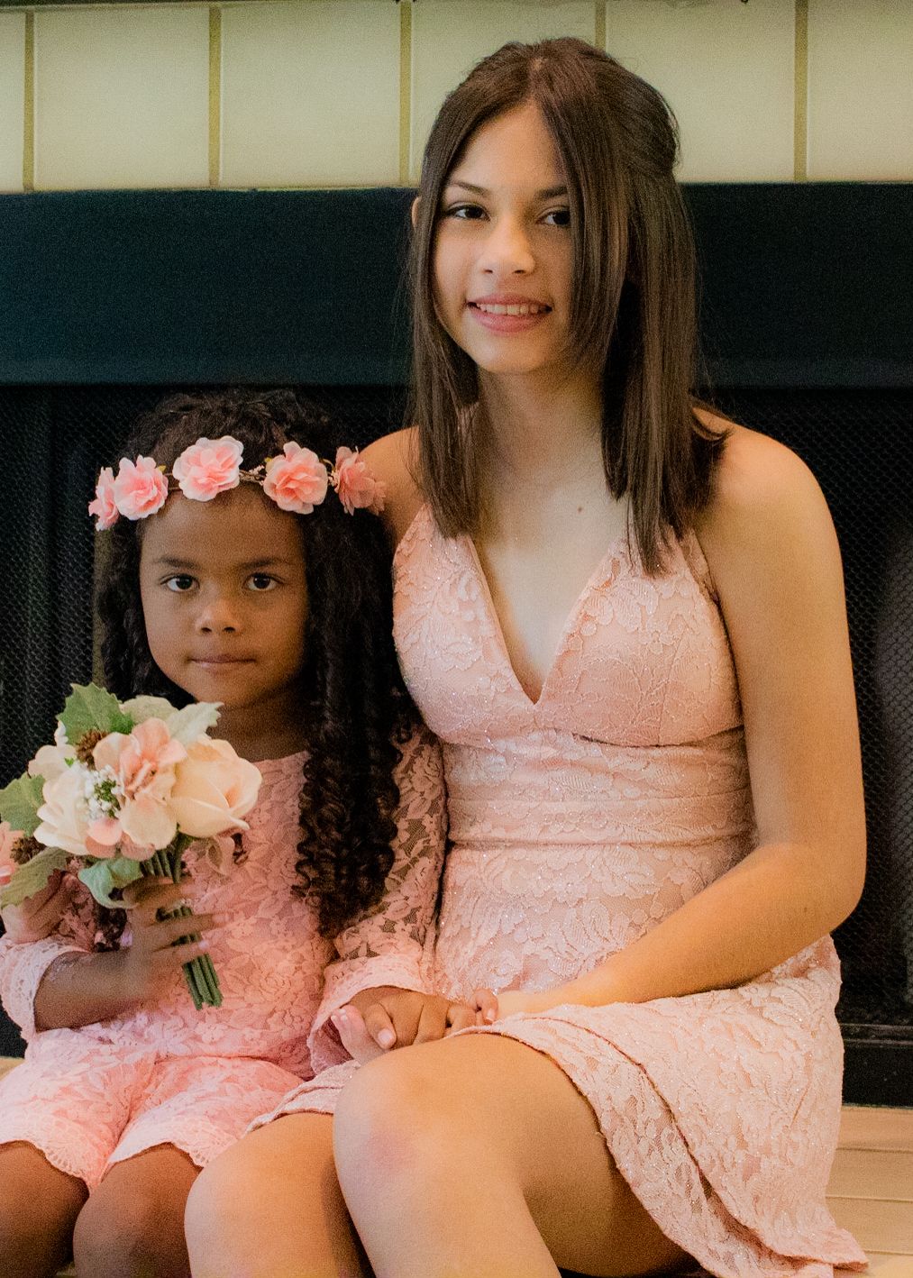 People wearing matching peach-colored dresses sitting together with floral bouquets.