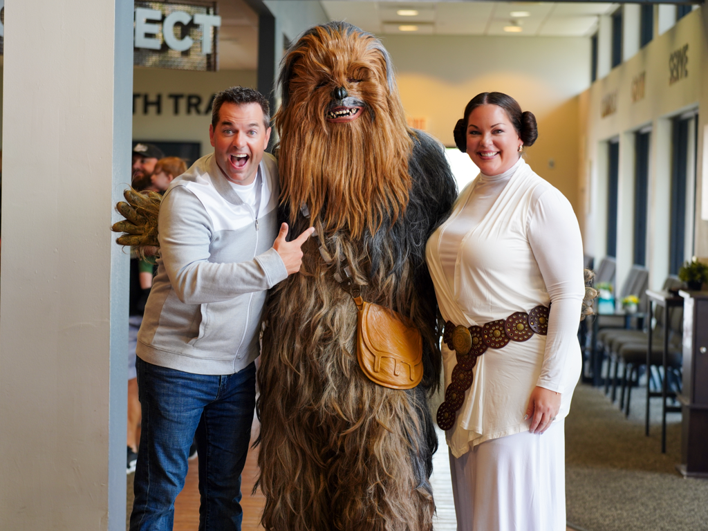 Star Wars cosplayers pose with Chewbacca in a convention center hallway.
