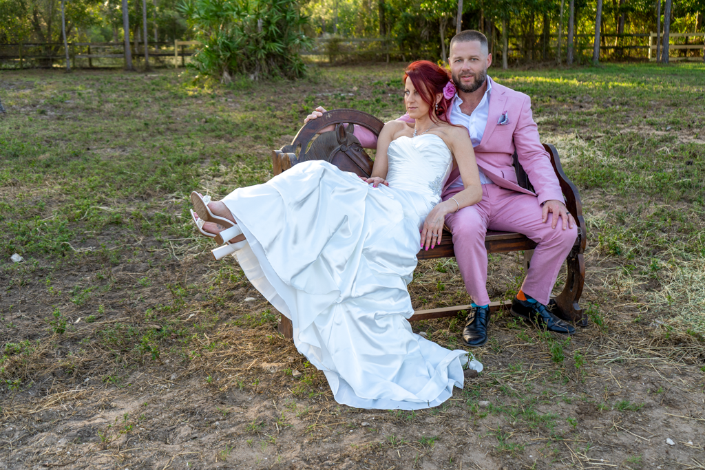 Wedding couple sitting together on grass during outdoor photo session.
