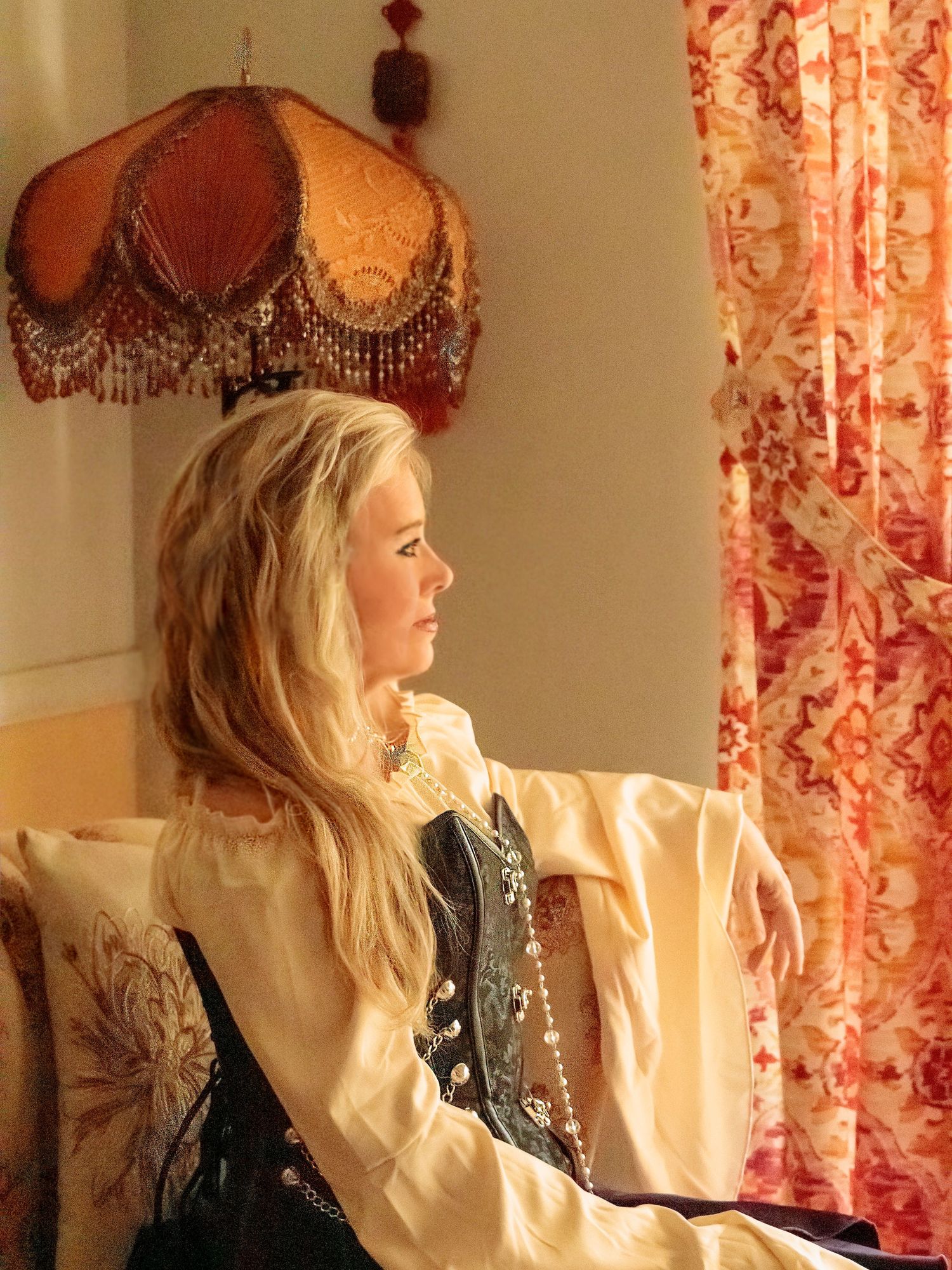 Sunlit profile view through vintage-style room with red floral curtains.