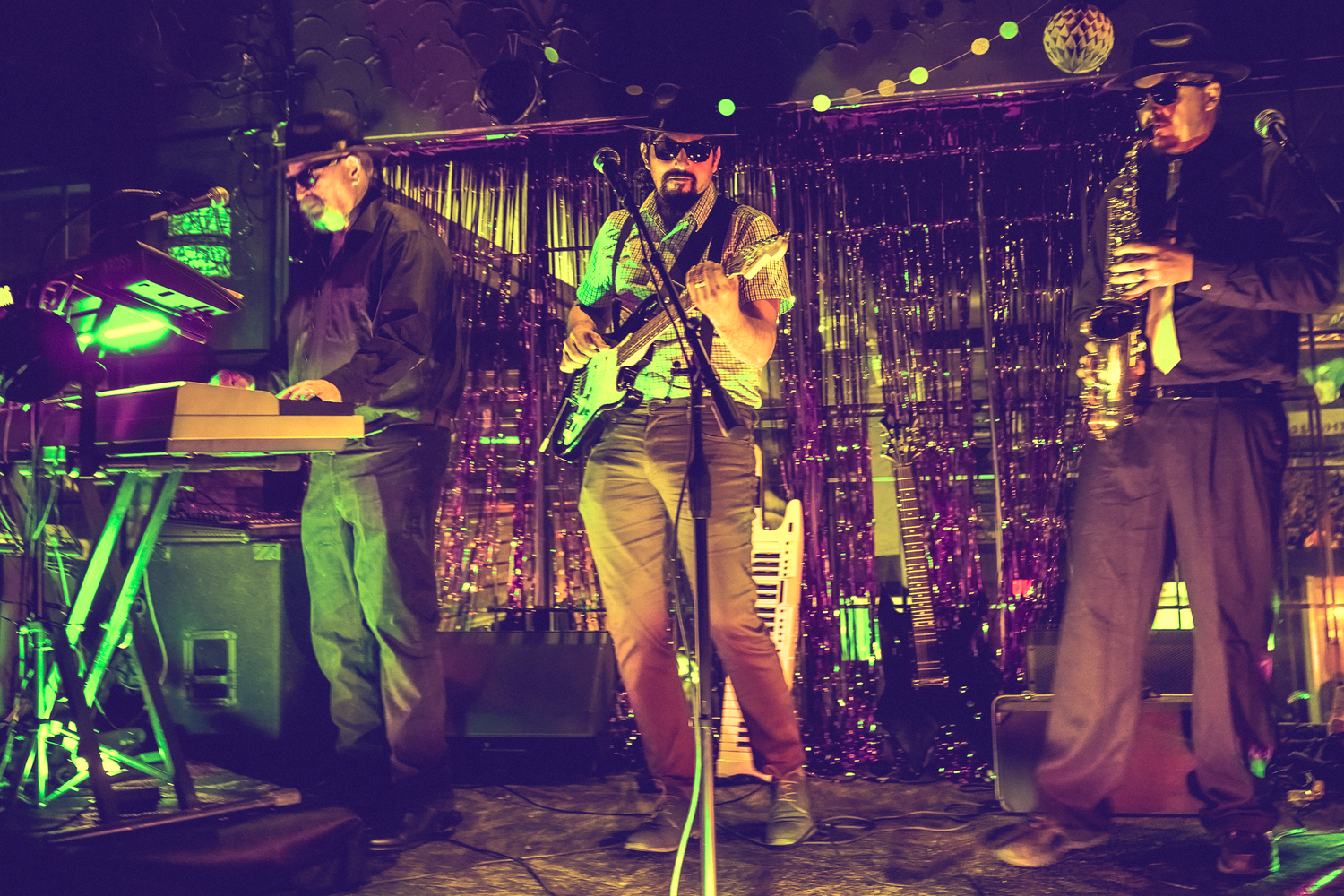 Band performing on stage with colorful lighting and instruments during a live concert performance.
