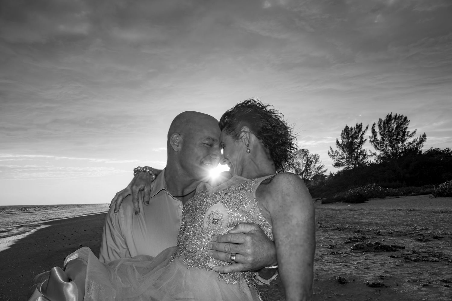 A silhouetted couple shares an intimate moment against a dramatic beach sunset.