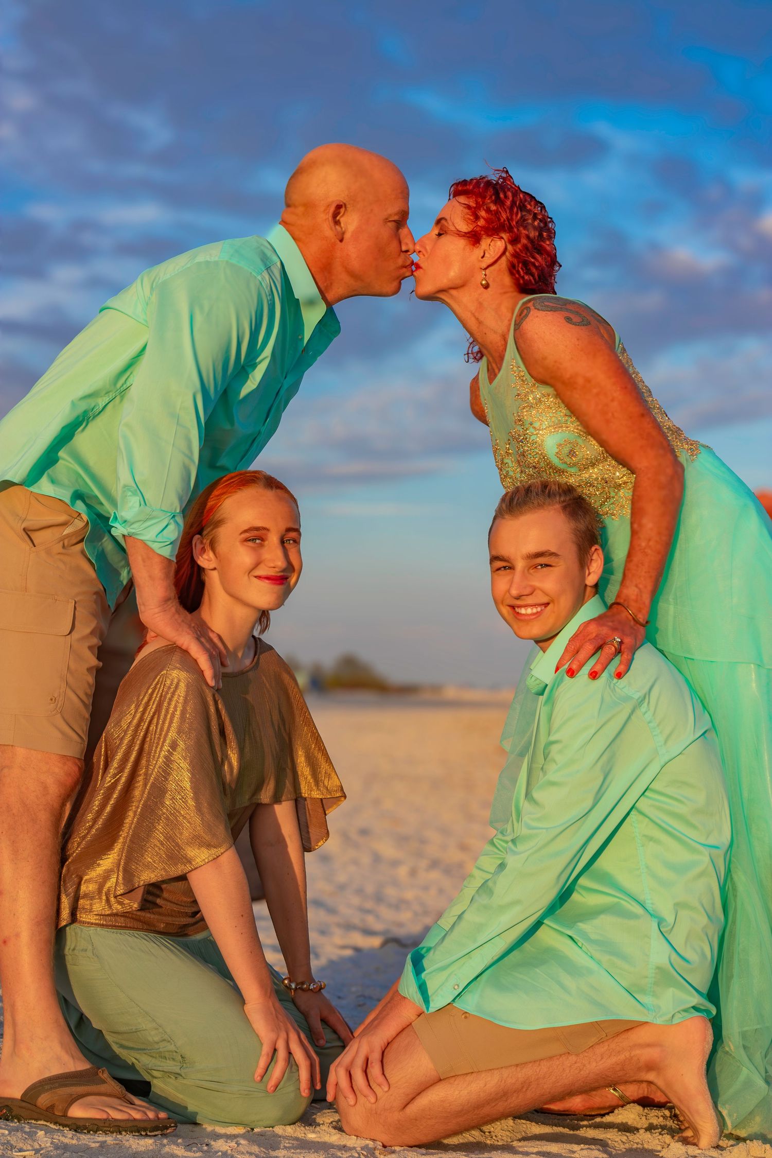 A couple in mint green outfits shares playful moments on a sandy beach.