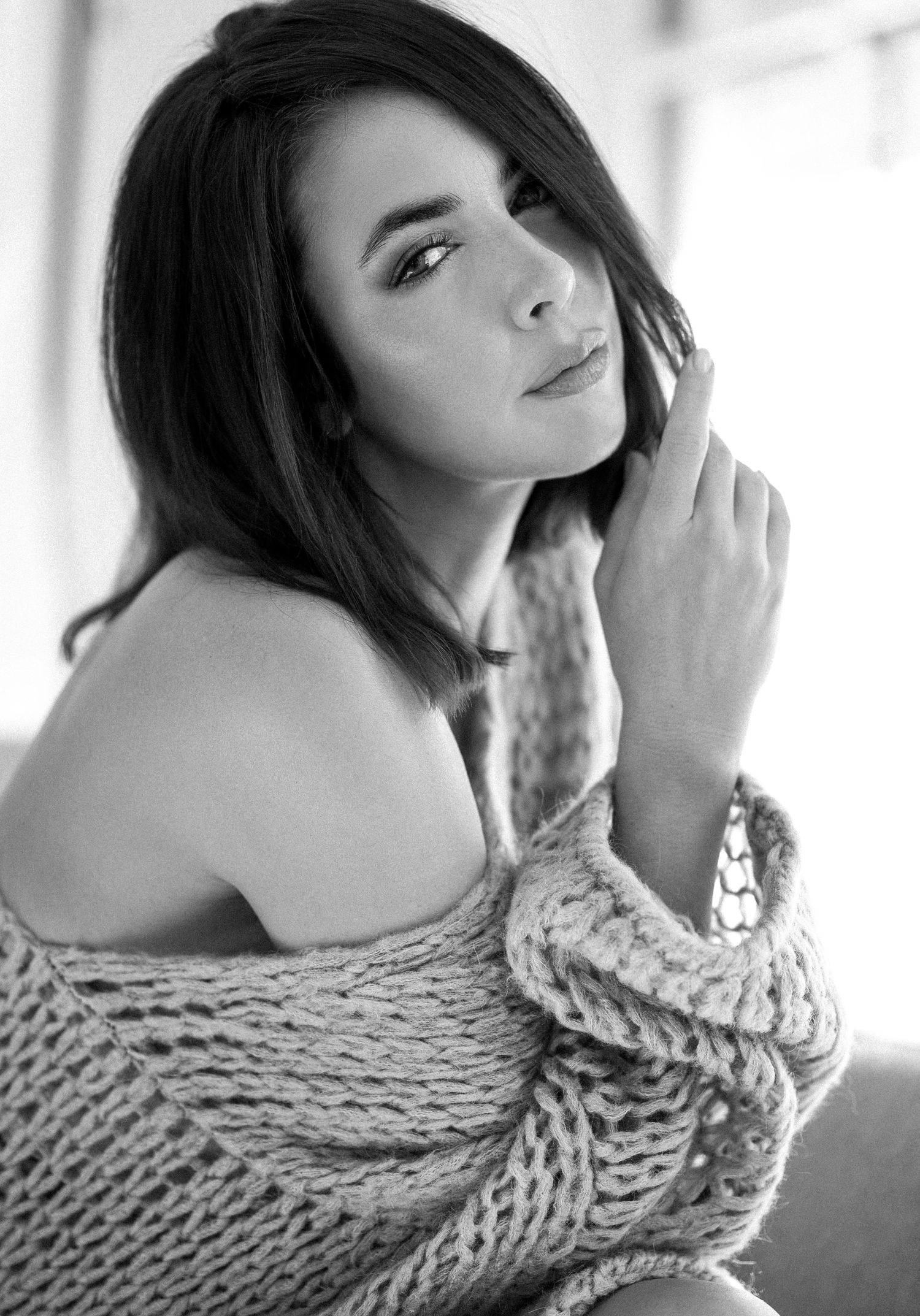 Black and white portrait series showing a woman in a chunky knit sweater posing against a light background.