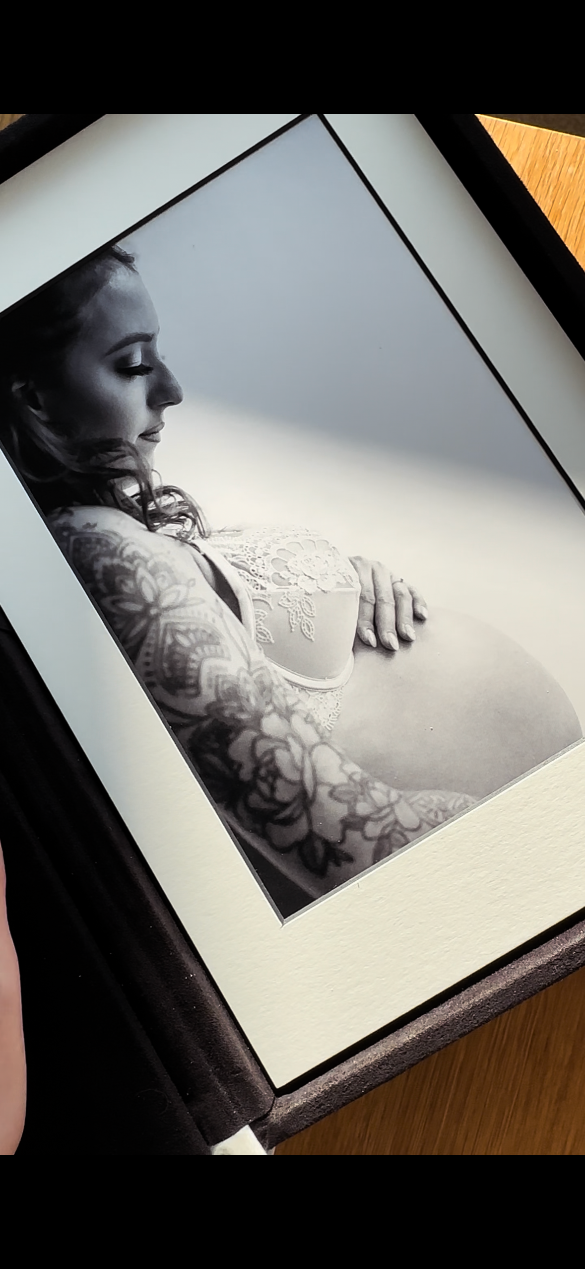 Black and white artistic photographs showing intricate tattoo details on skin in dramatic lighting.