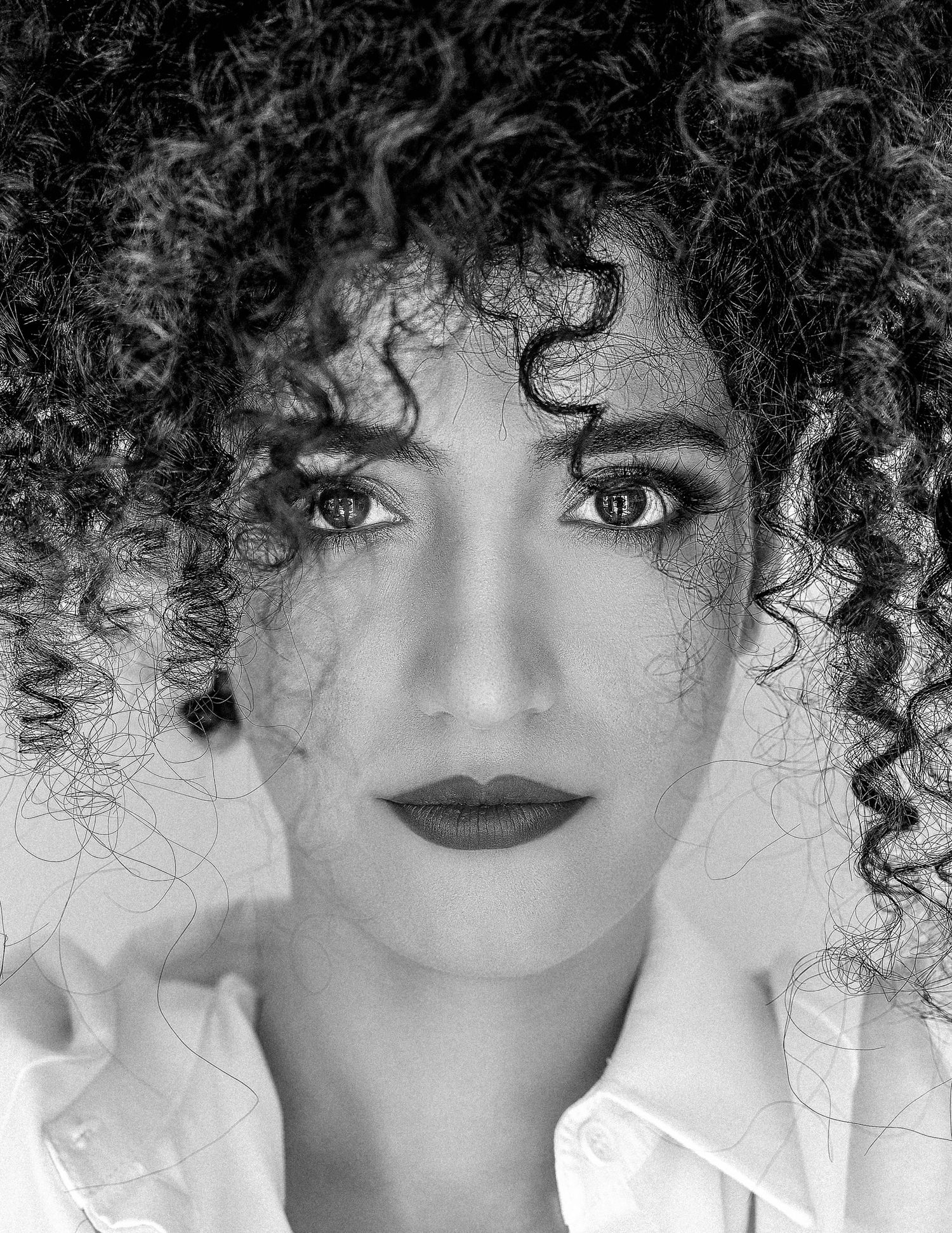 High contrast black and white beauty portraits featuring dramatic curls and white clothing.