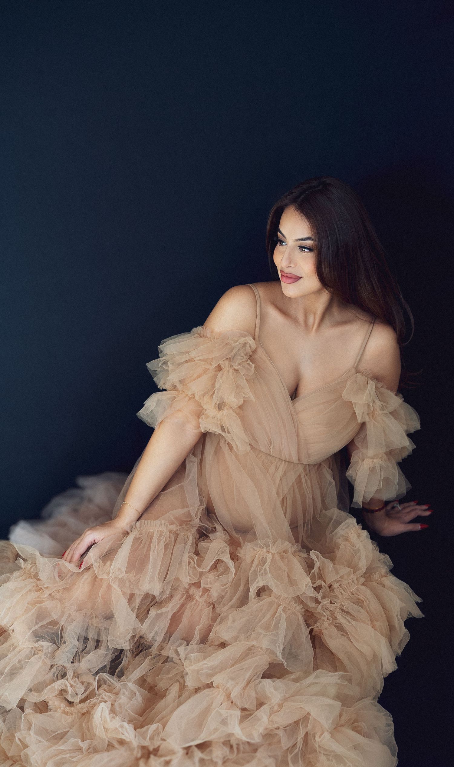 Dramatic fashion portraits in a flowing champagne-colored tulle gown against dark background.