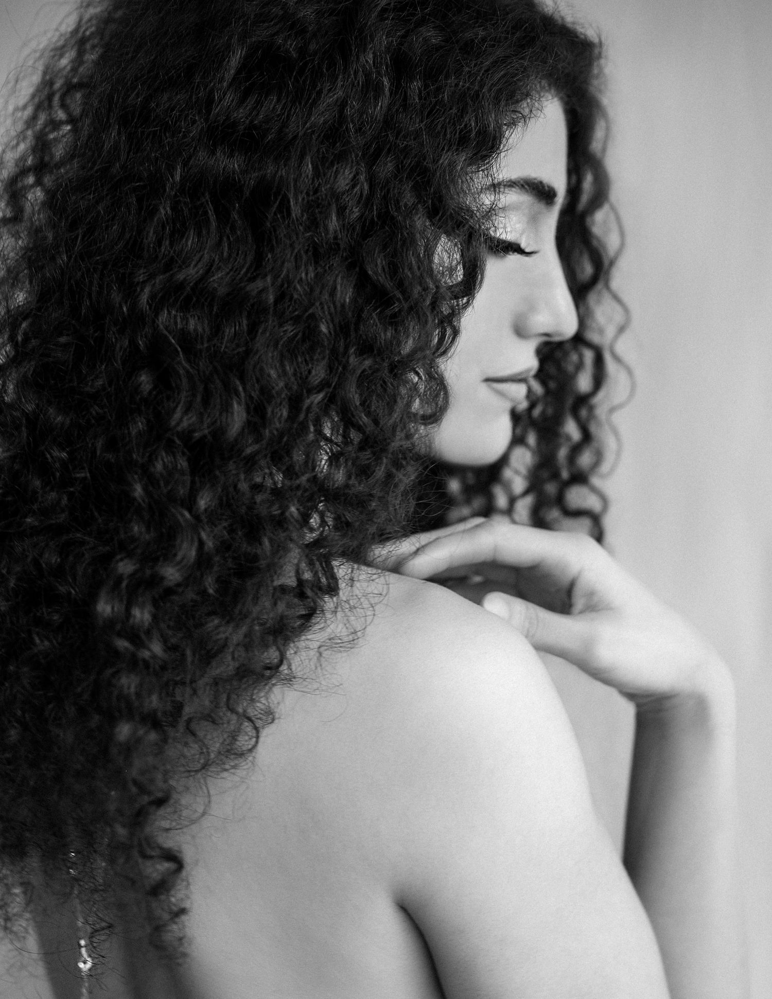 A black and white artistic portrait series showing a person with curly hair in profile against a light background.