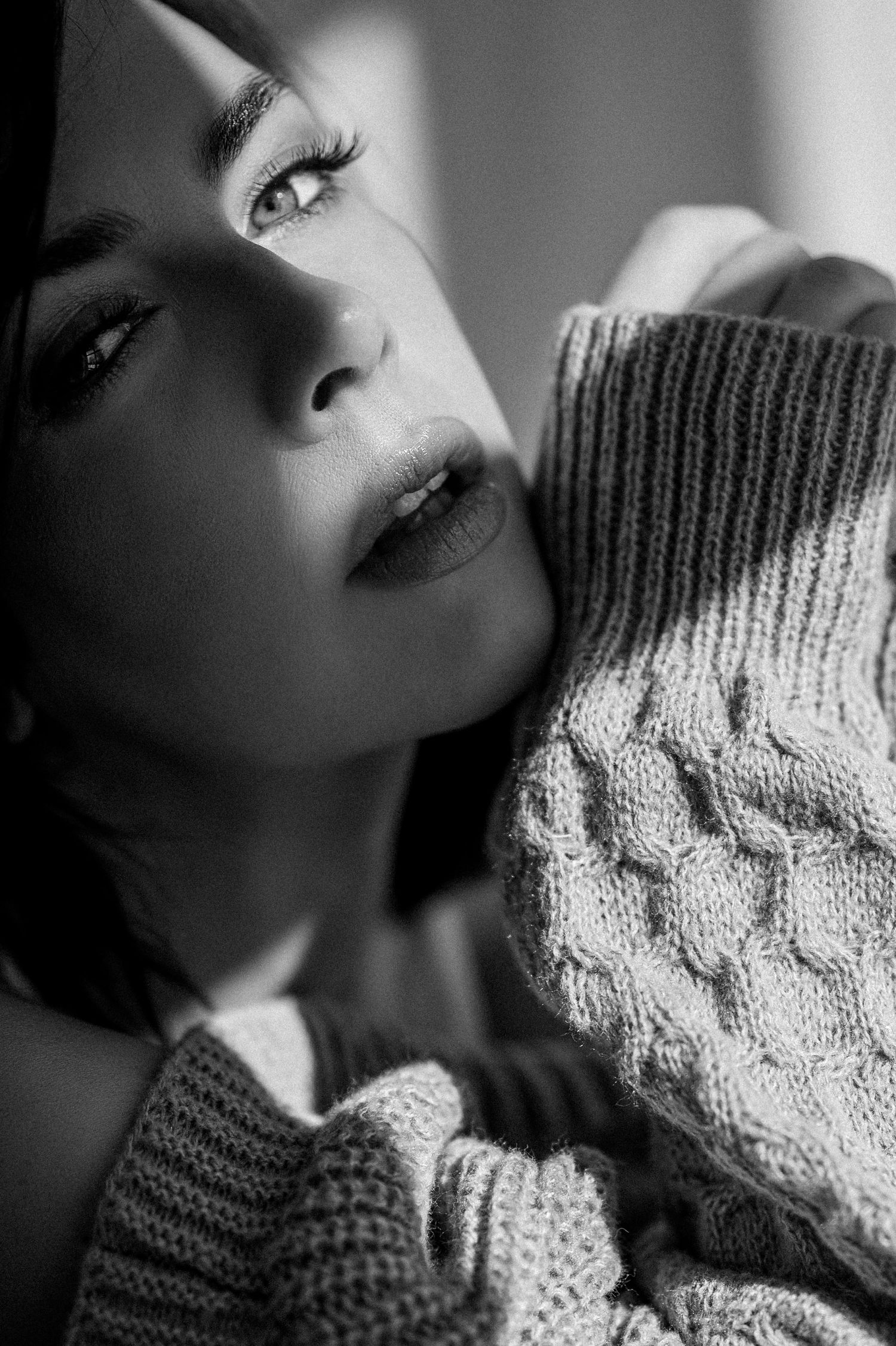 Dramatic black and white portrait series showing person wearing cozy knit sweater in moody lighting.