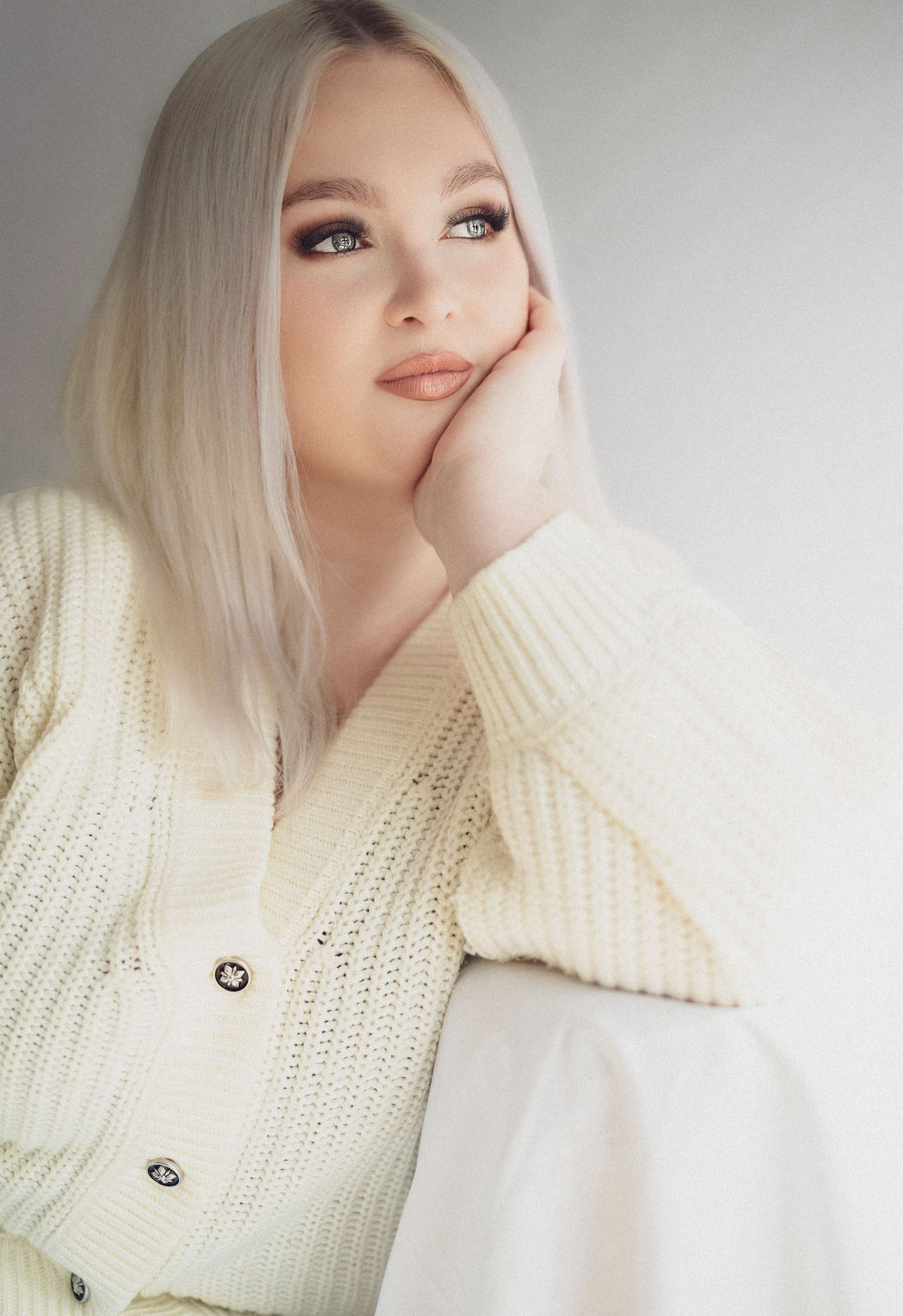 Soft portraits wearing cream knit sweater against light background.