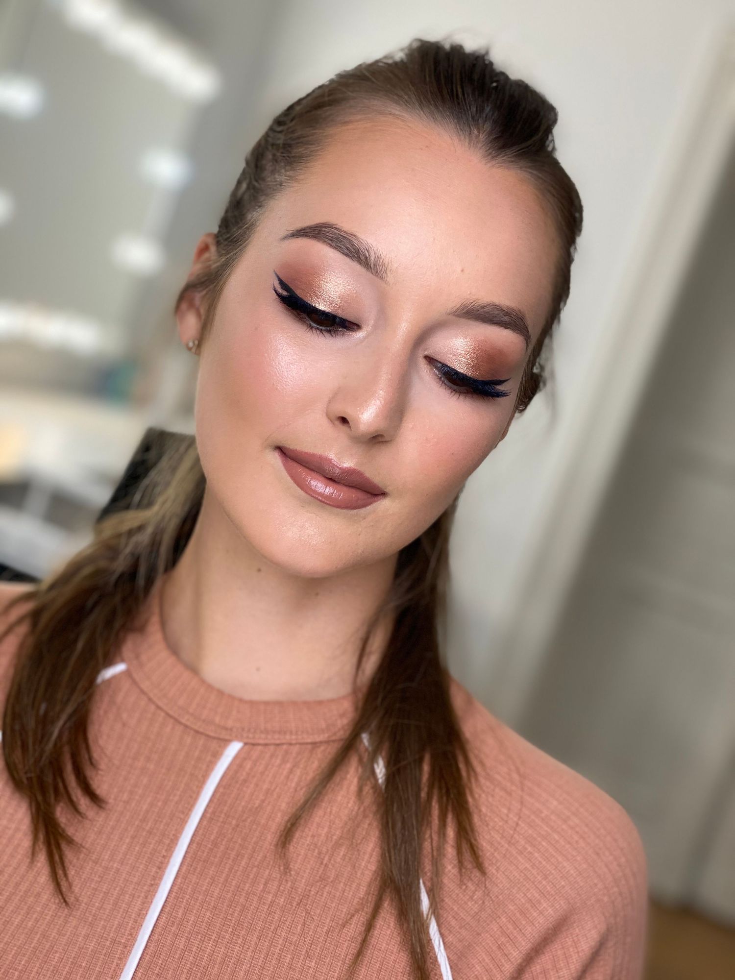 Close-up beauty portrait showing glamorous makeup and pink turtleneck sweater in studio lighting.