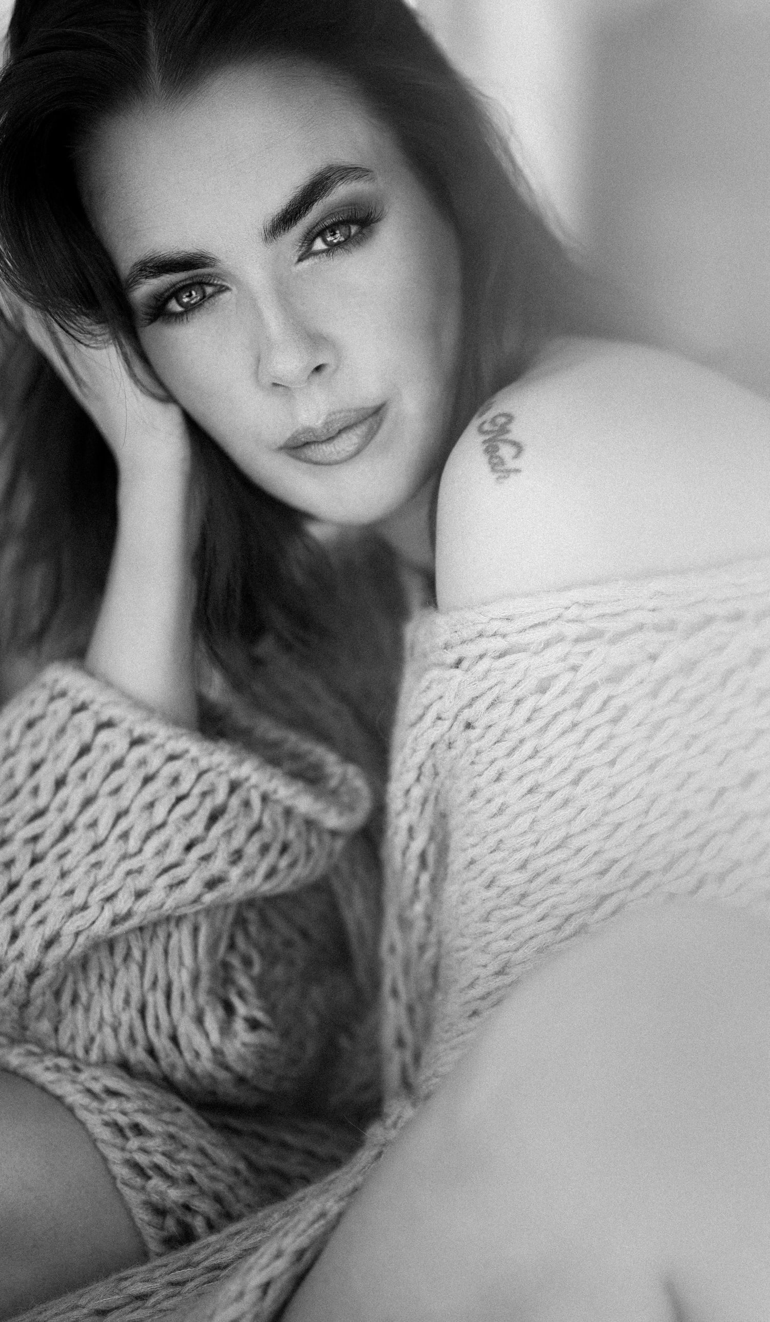 Black and white portrait series showing a person in a knit sweater posing with expressive eyes and soft lighting.