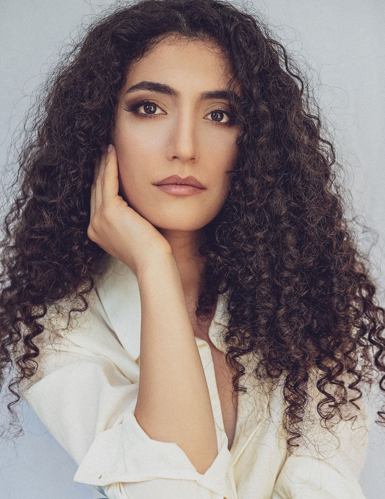 Studio portrait series featuring natural curly hair and classic white button-down styling.