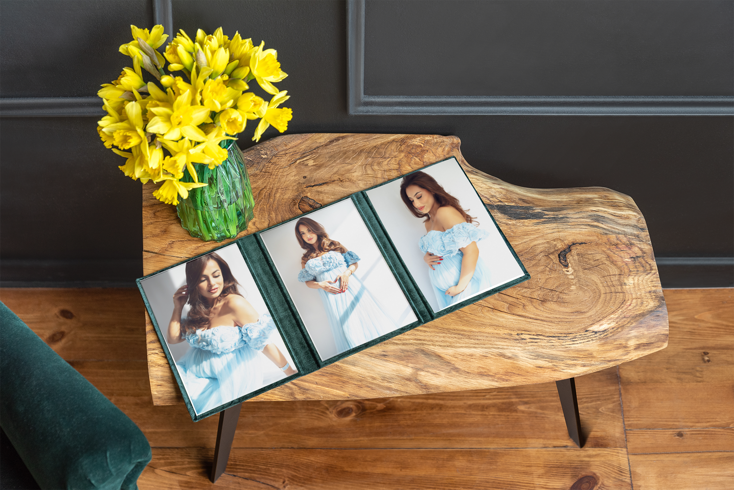 Yellow daffodils in a vase sit beside photo albums arranged on a rustic wooden table surface.