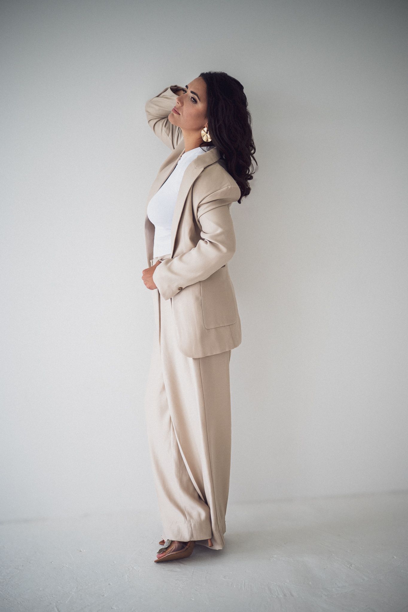 Contemporary fashion portraits showing dynamic poses in neutral toned outfit.