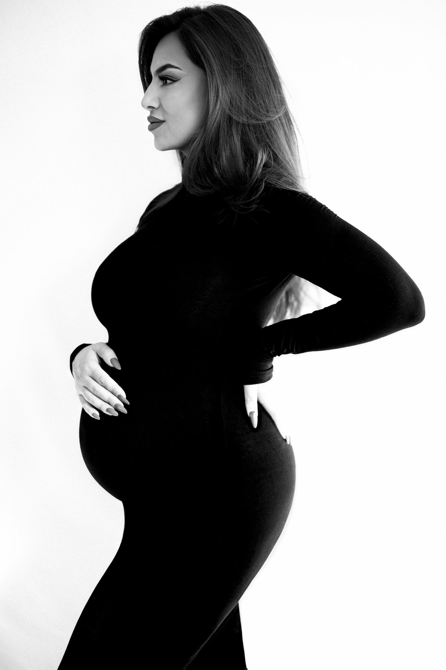 Dramatic black and white silhouette series of a pregnant woman in dark clothing.