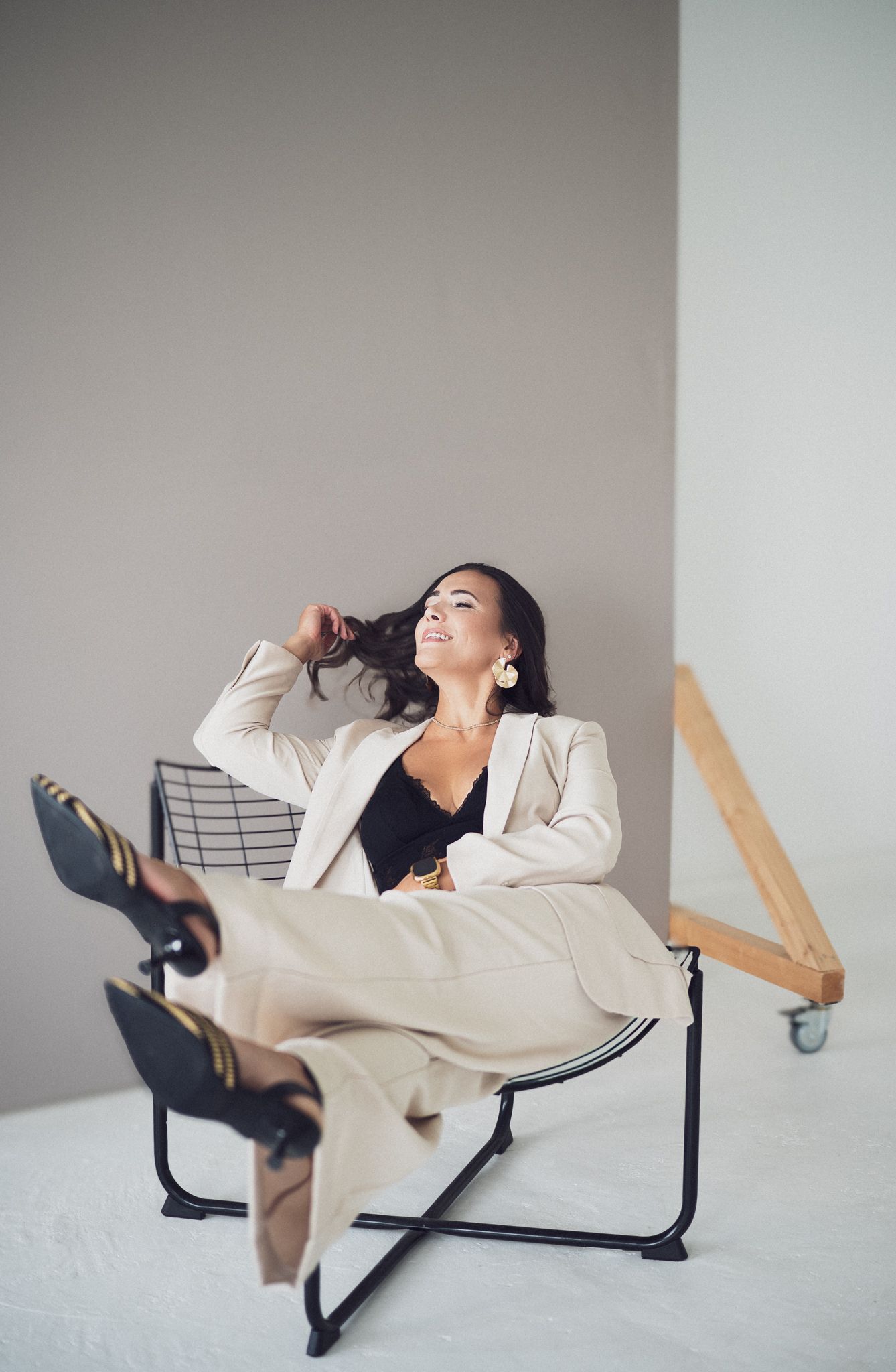 Dynamic poses captured of person lounging in cream blazer on modern furniture.