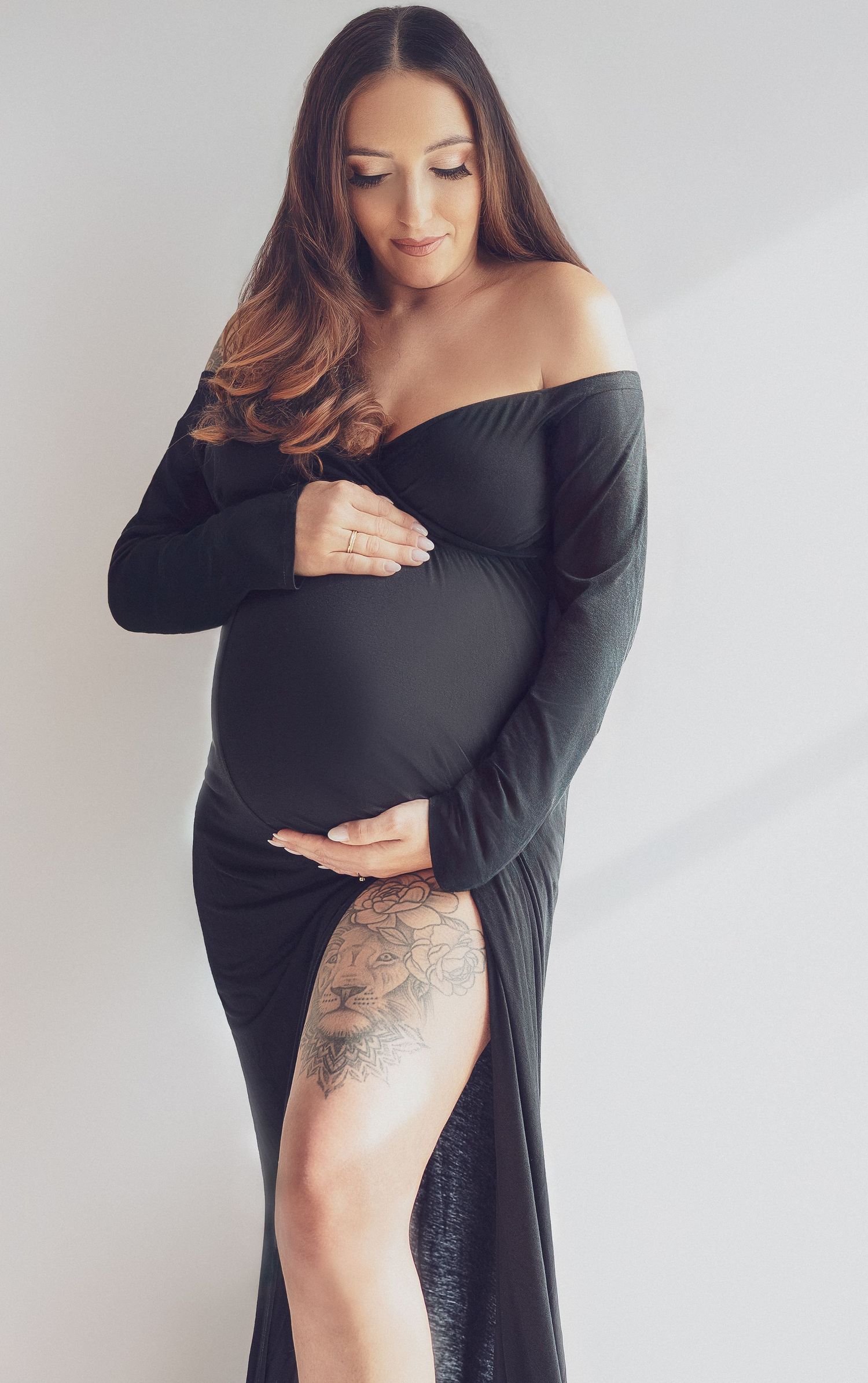 Modern maternity photography with woman in black dress showing side profile.