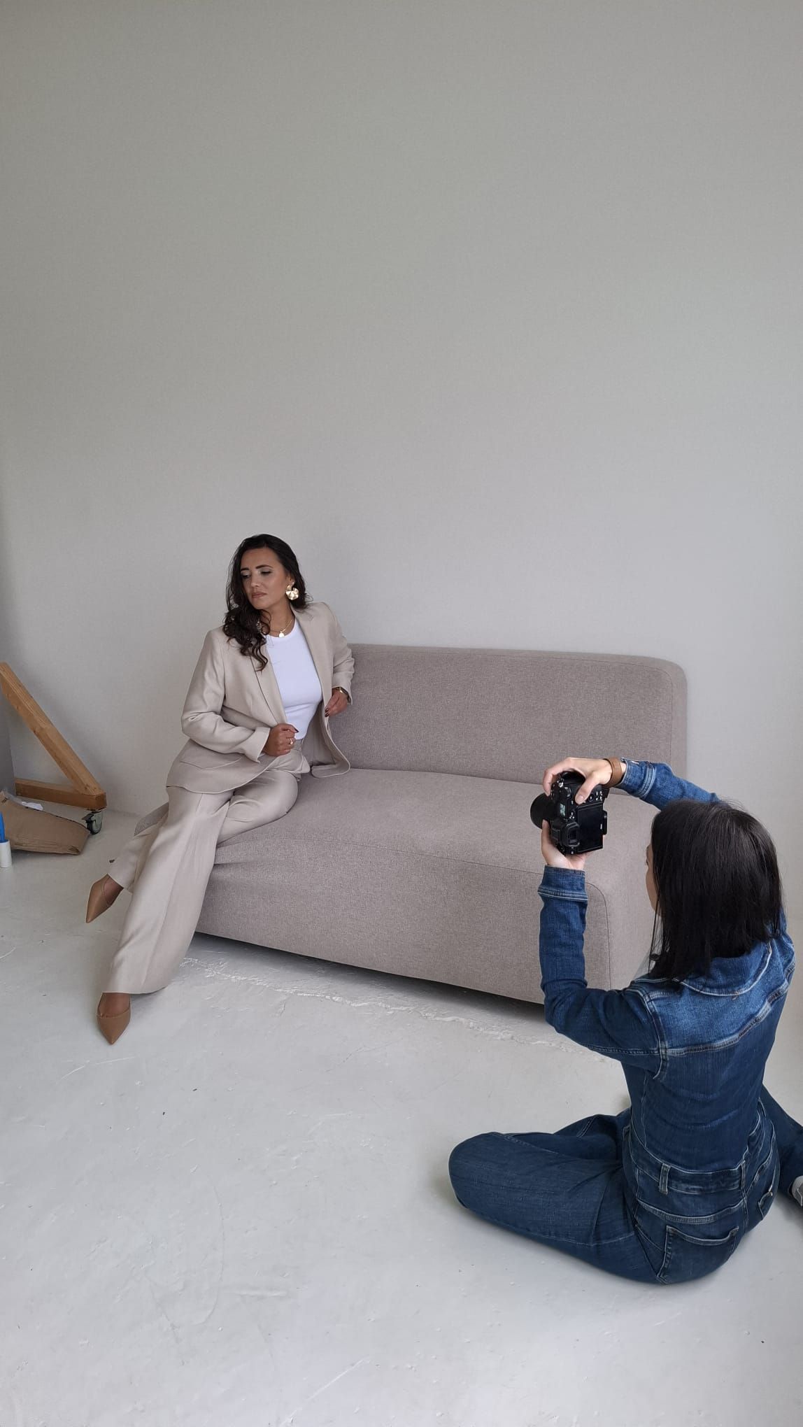 Behind the scenes photo session showing photographer and model working on couch.