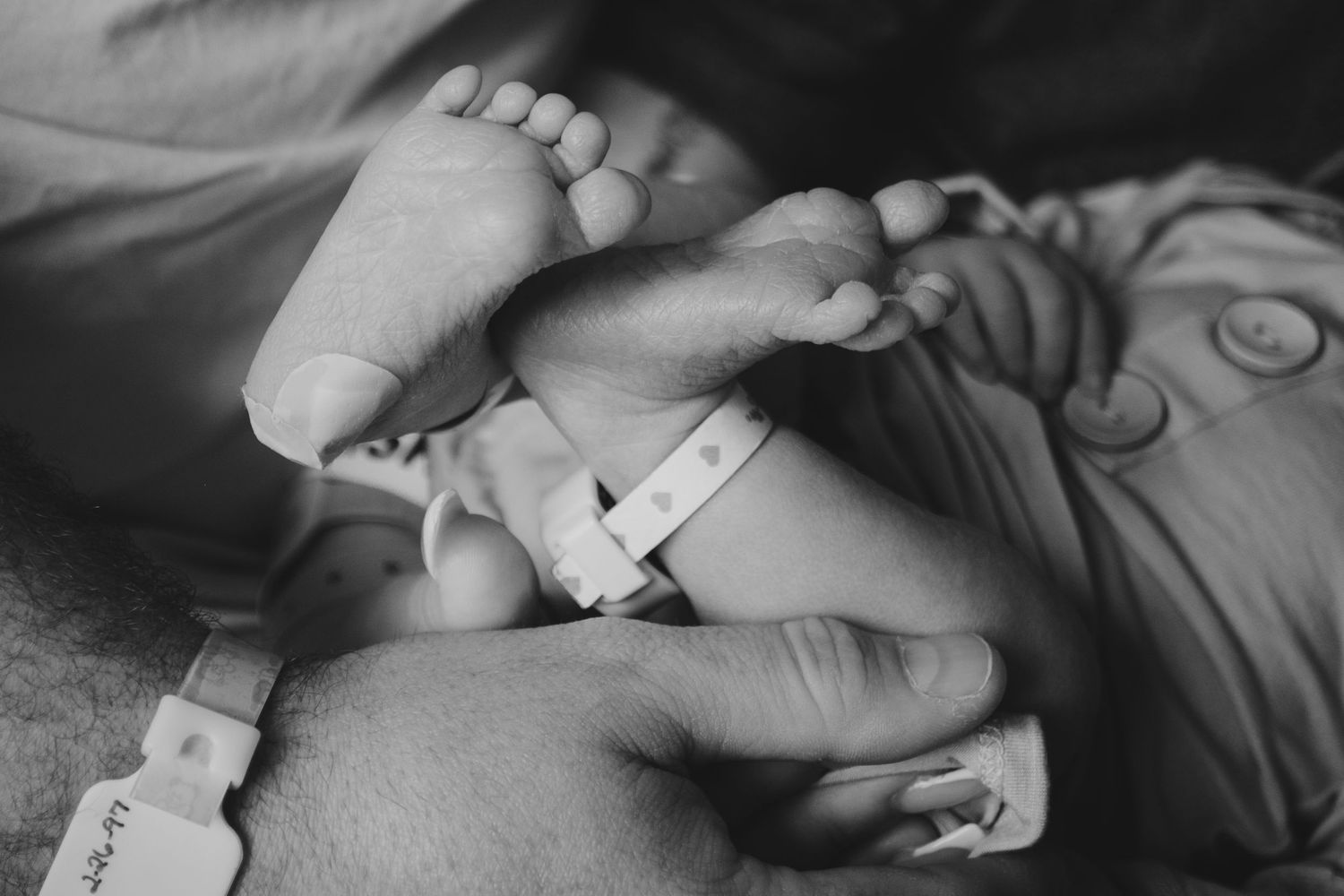 A dad gently holding his newborn son's feet in Fort Worth, TX
