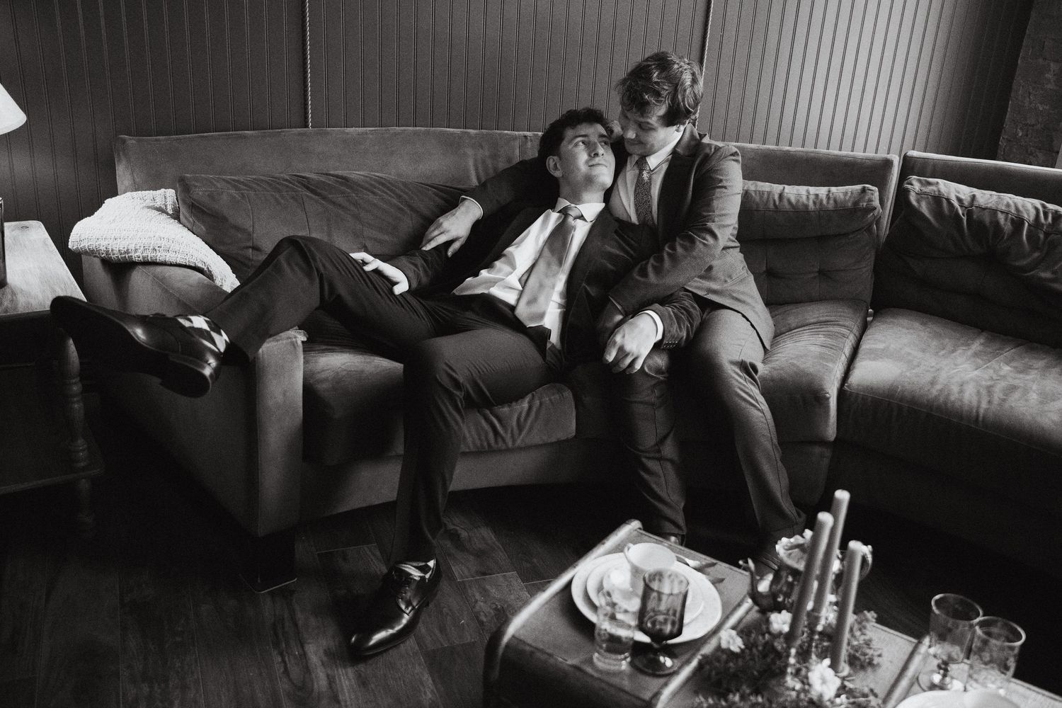 Two grooms lounging on a couch and looking at each other lovingly