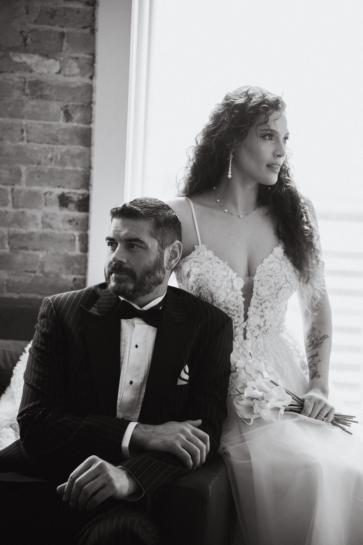 A bride and groom posing in front of a bright window