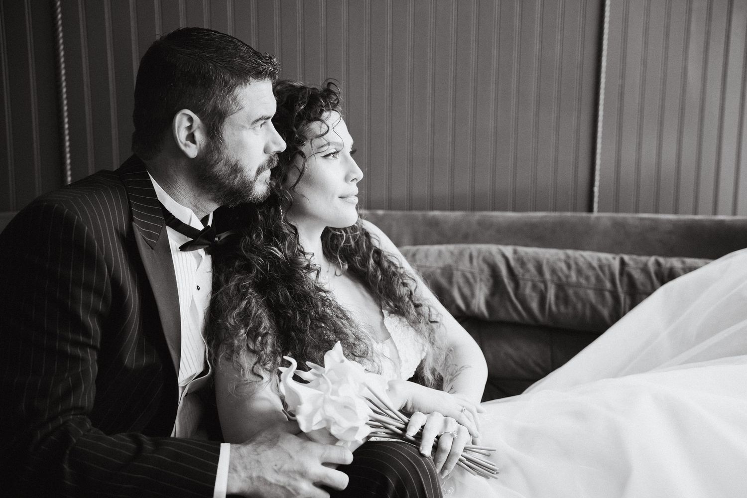 A bride and groom posing on a velvet couch
