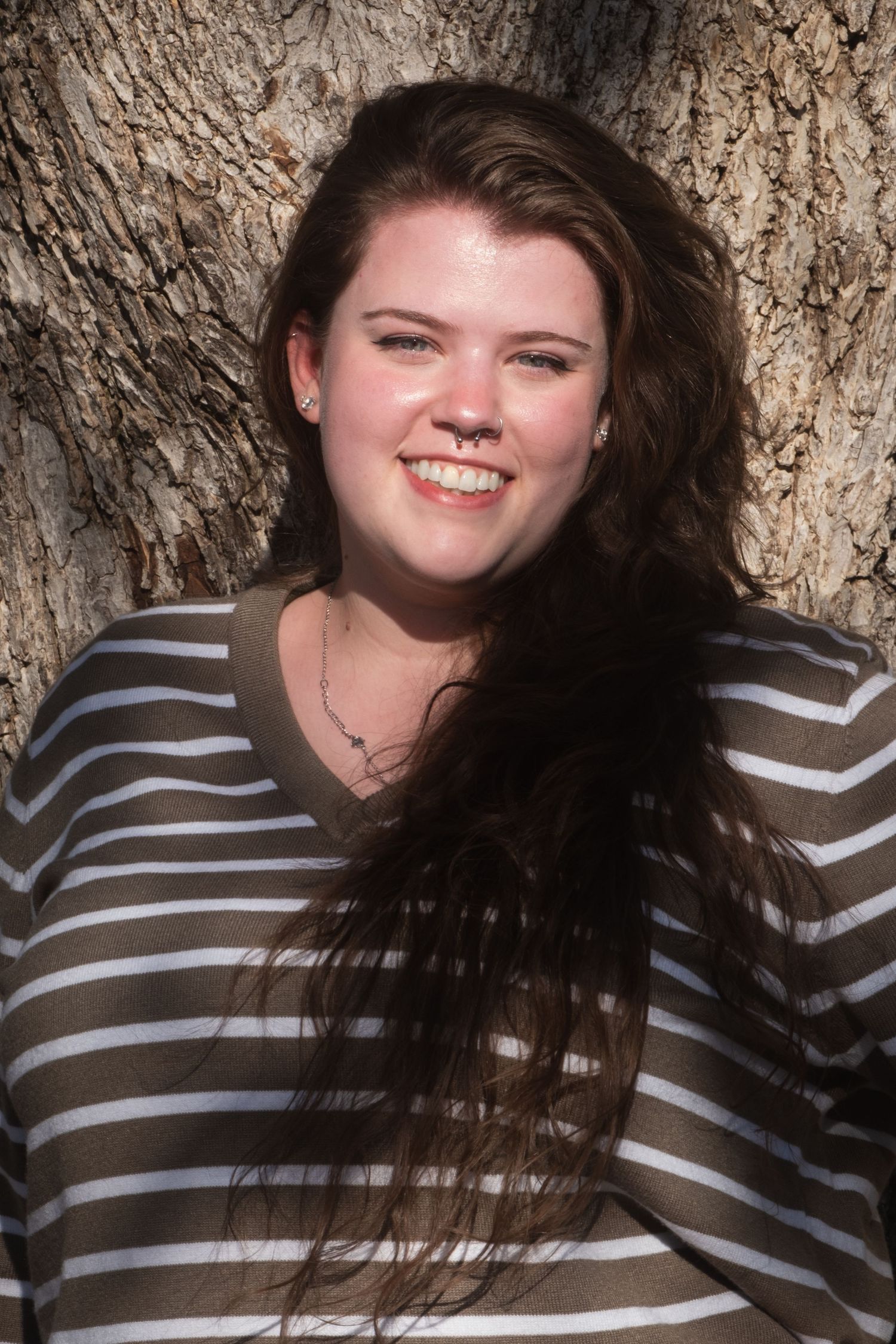 A woman smiling by a tree in downtown Denton, TX