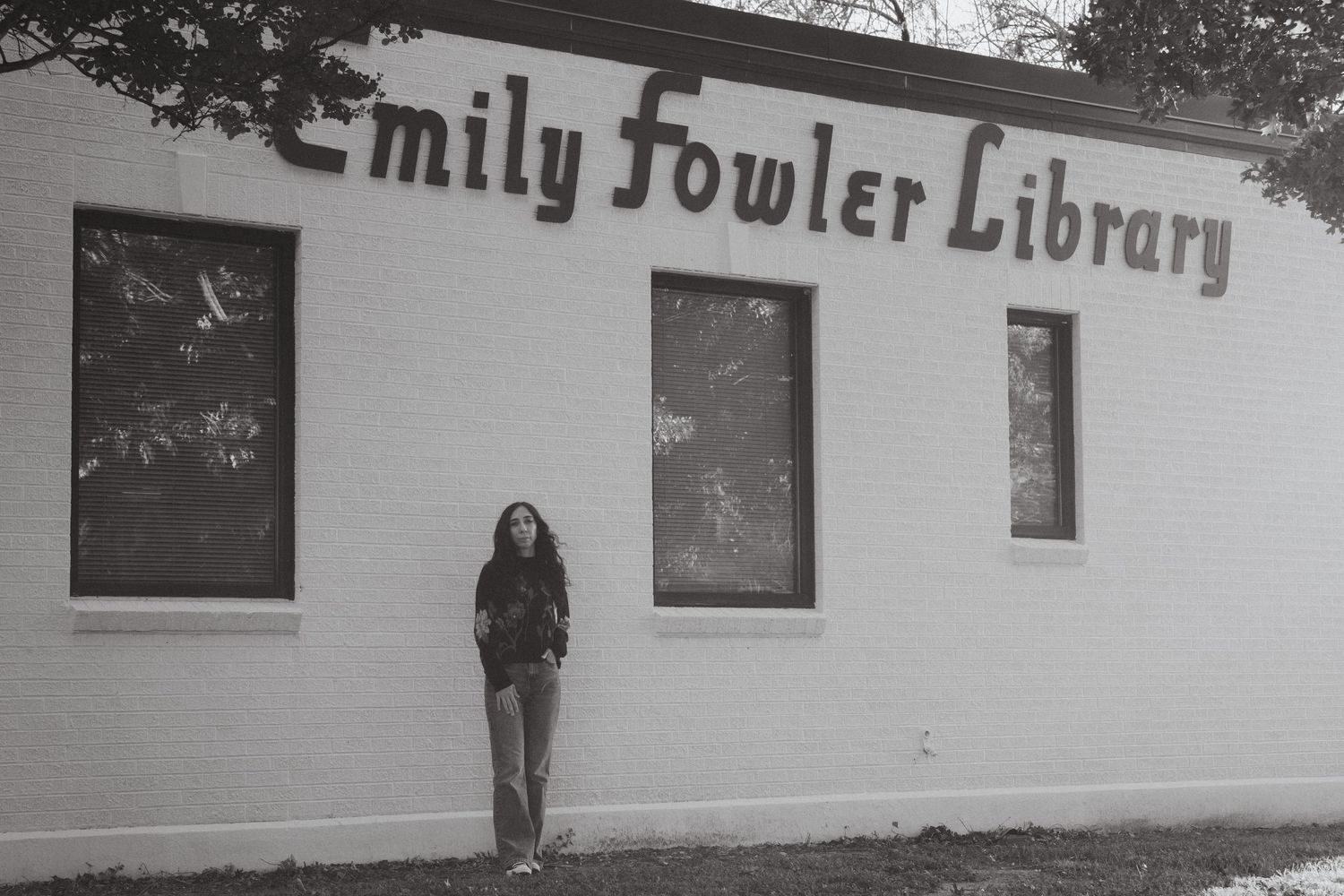 A librarian posing in front of Emily Fowler Library in Denton, TX.
