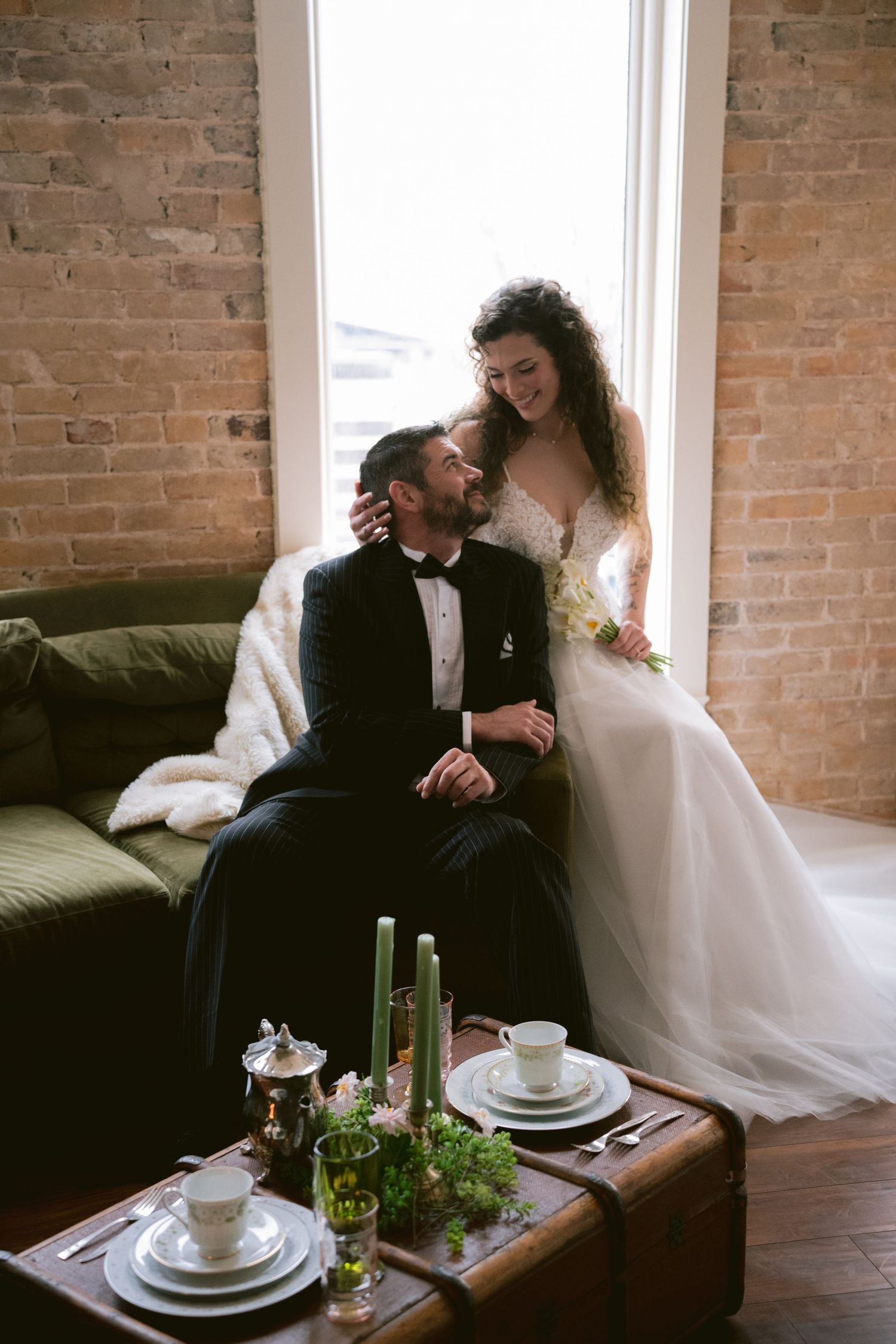 A bride and groom posing in front of a bright window