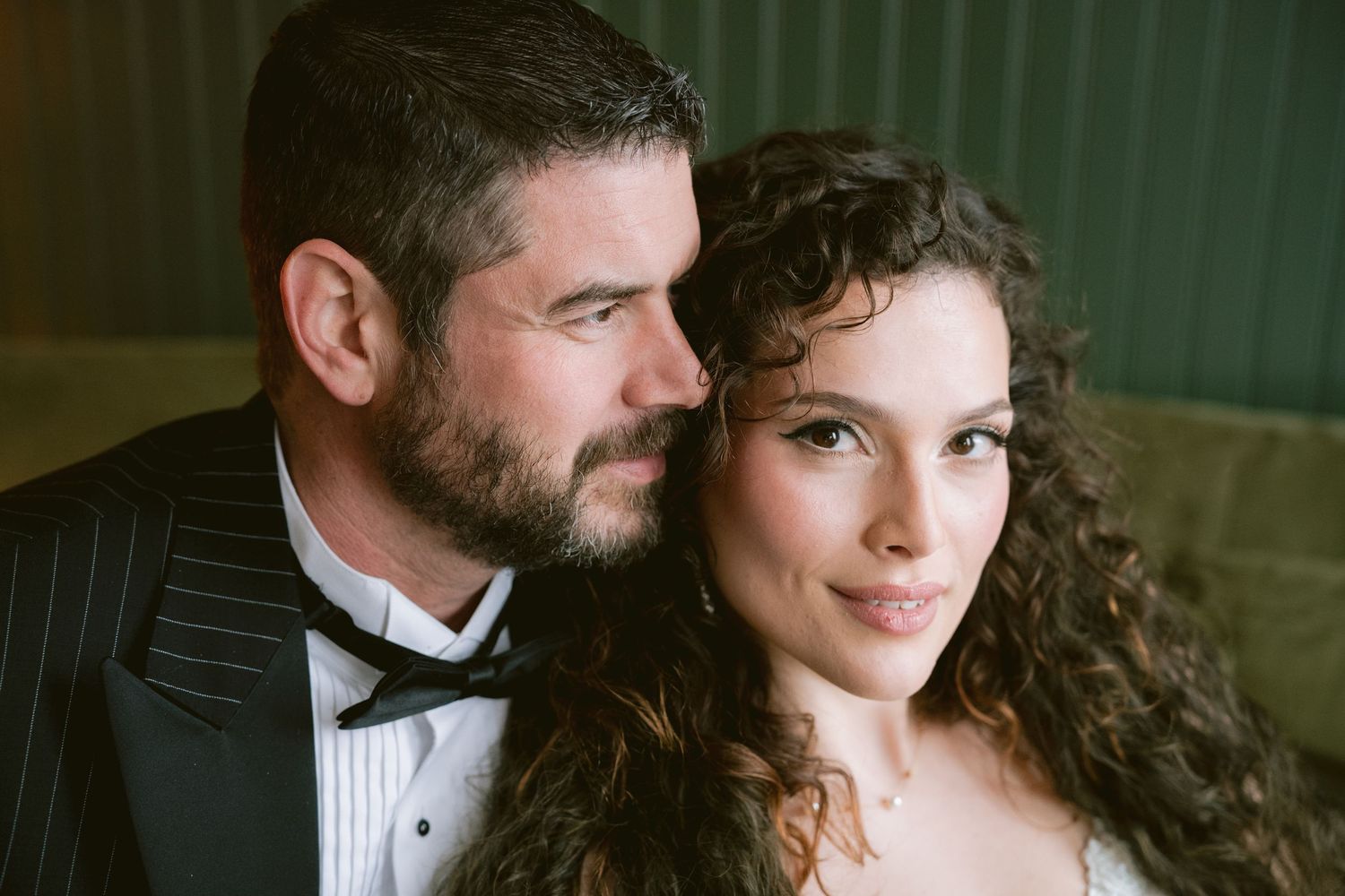 A bride and groom posing on a velvet couch