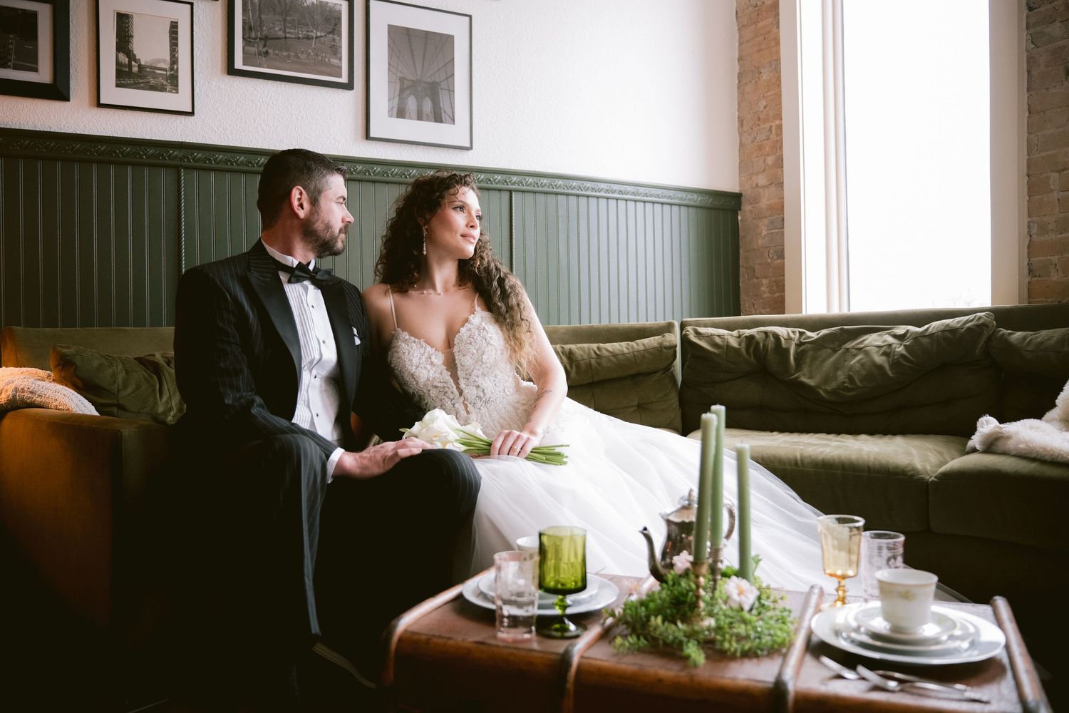 A bride and groom posing on a velvet couch
